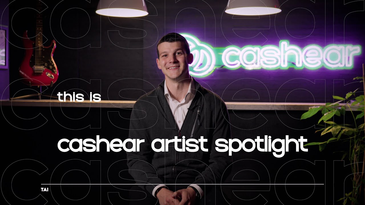 Tai smiling in a dark zip jacket over a white shirt on the Artist Spotlight set