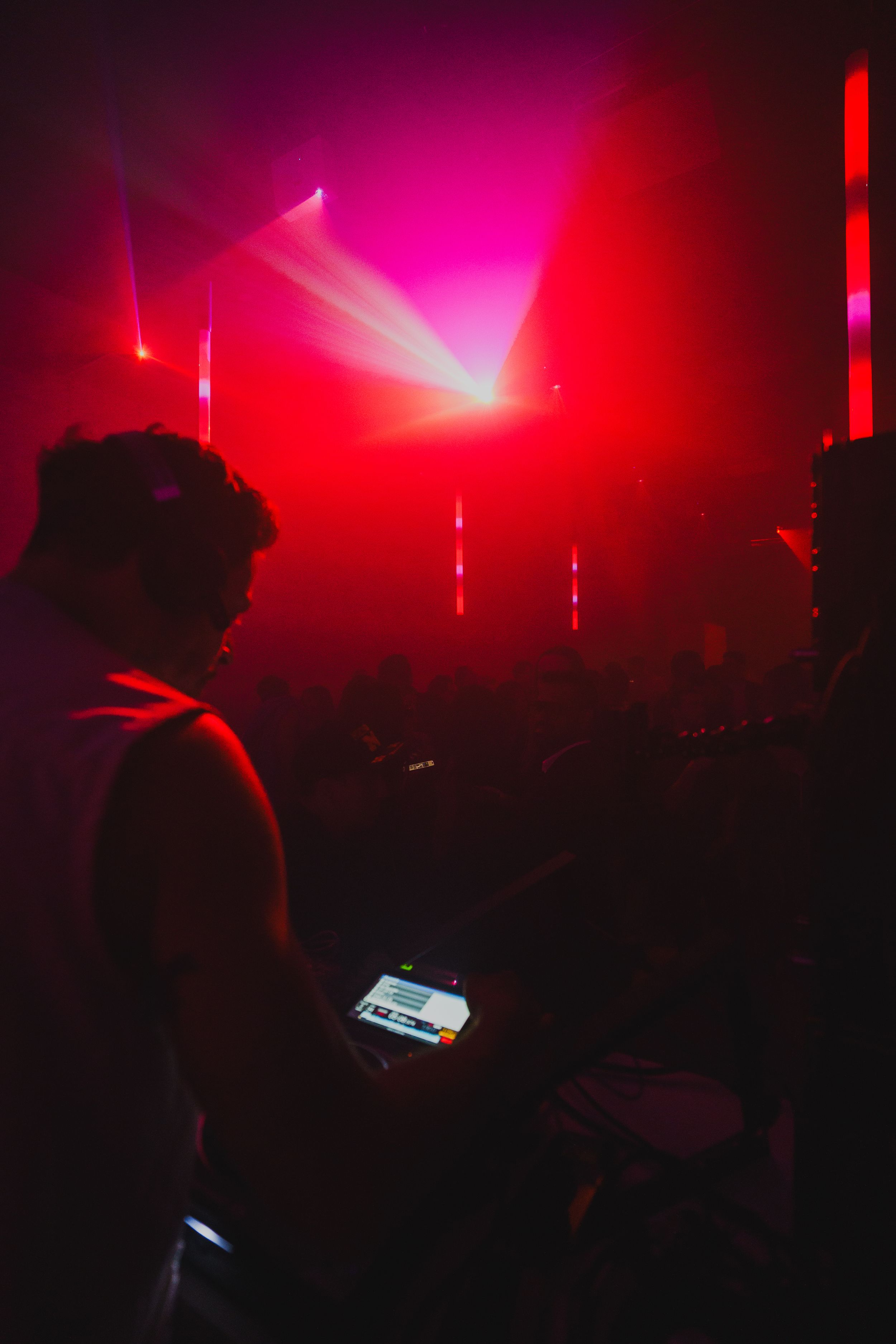 A guest silhouetted against magenta beams and vertical light strips, holding a phone at their side