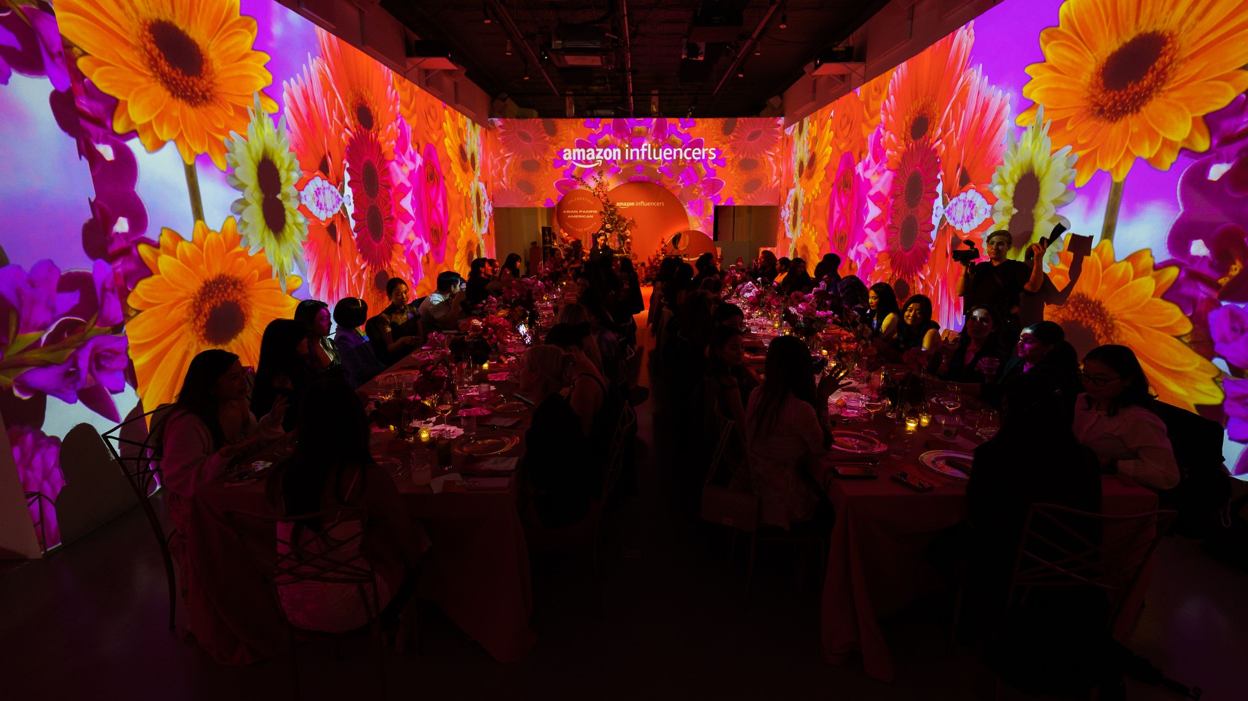 Long banquet tables running through a room wrapped floor to ceiling in projected sunflowers