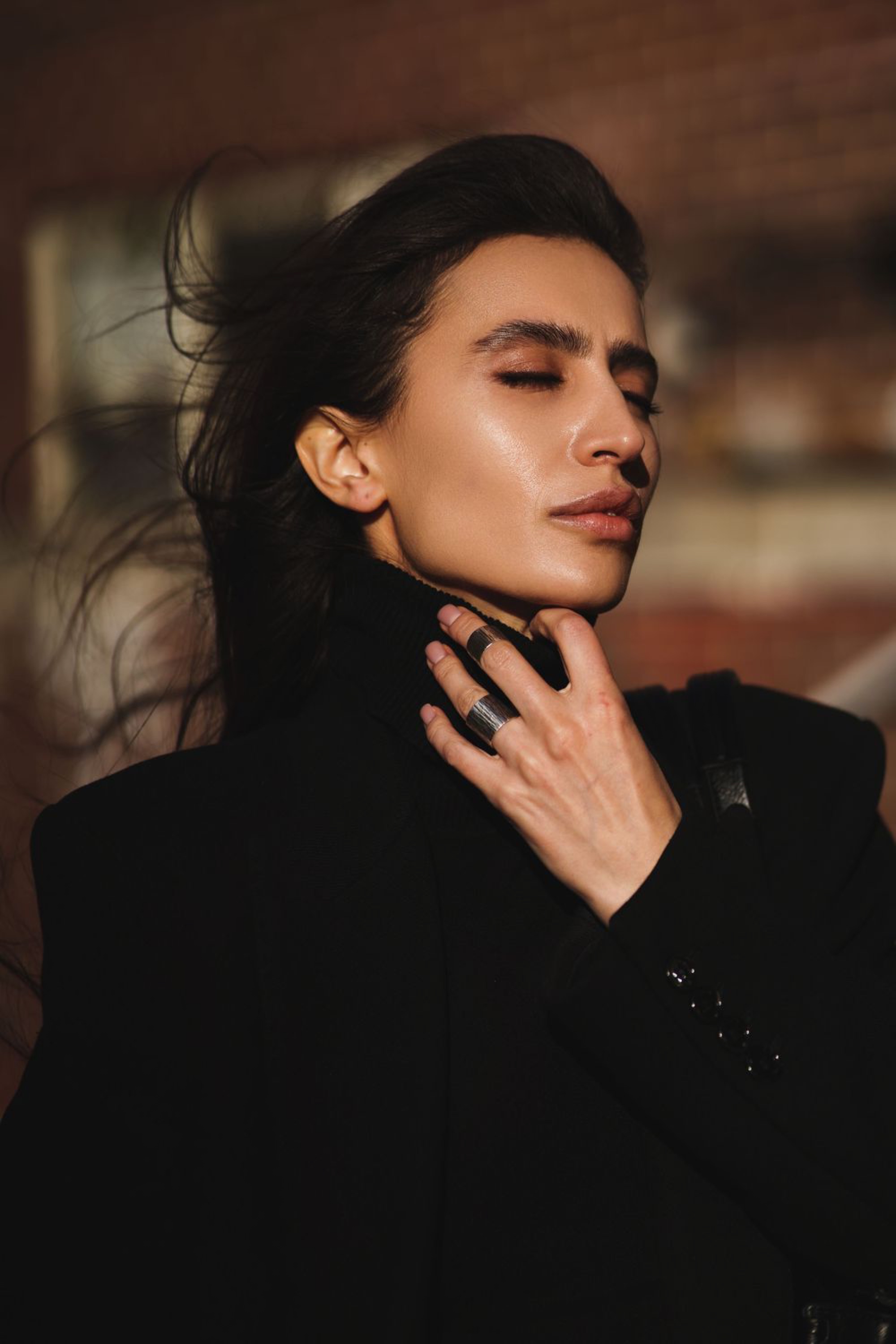 Dramatic fashion portrait in warm light of a model in a black turtleneck with windswept hair