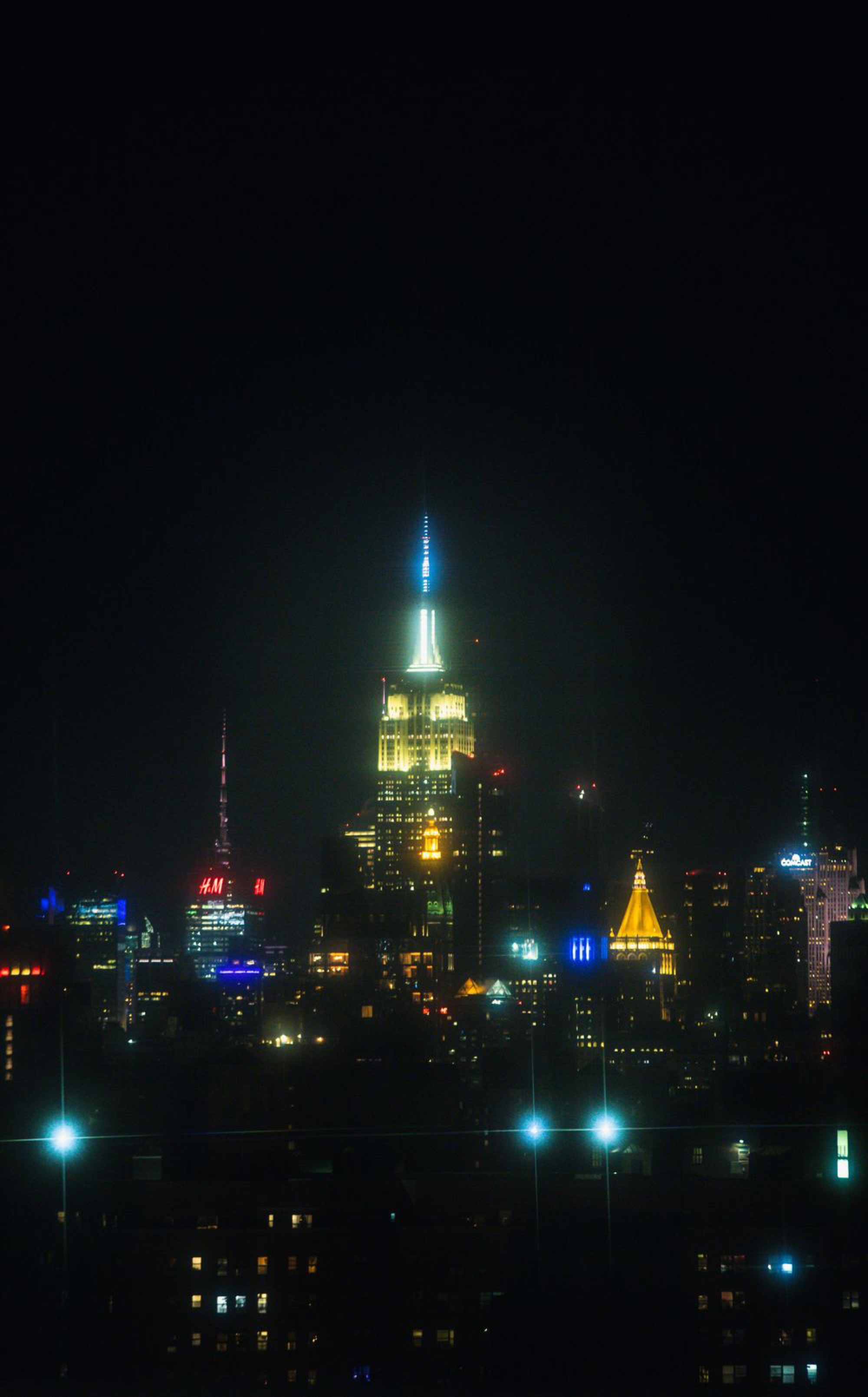 Empire State Building illuminated at night against a dark sky filled with city lights