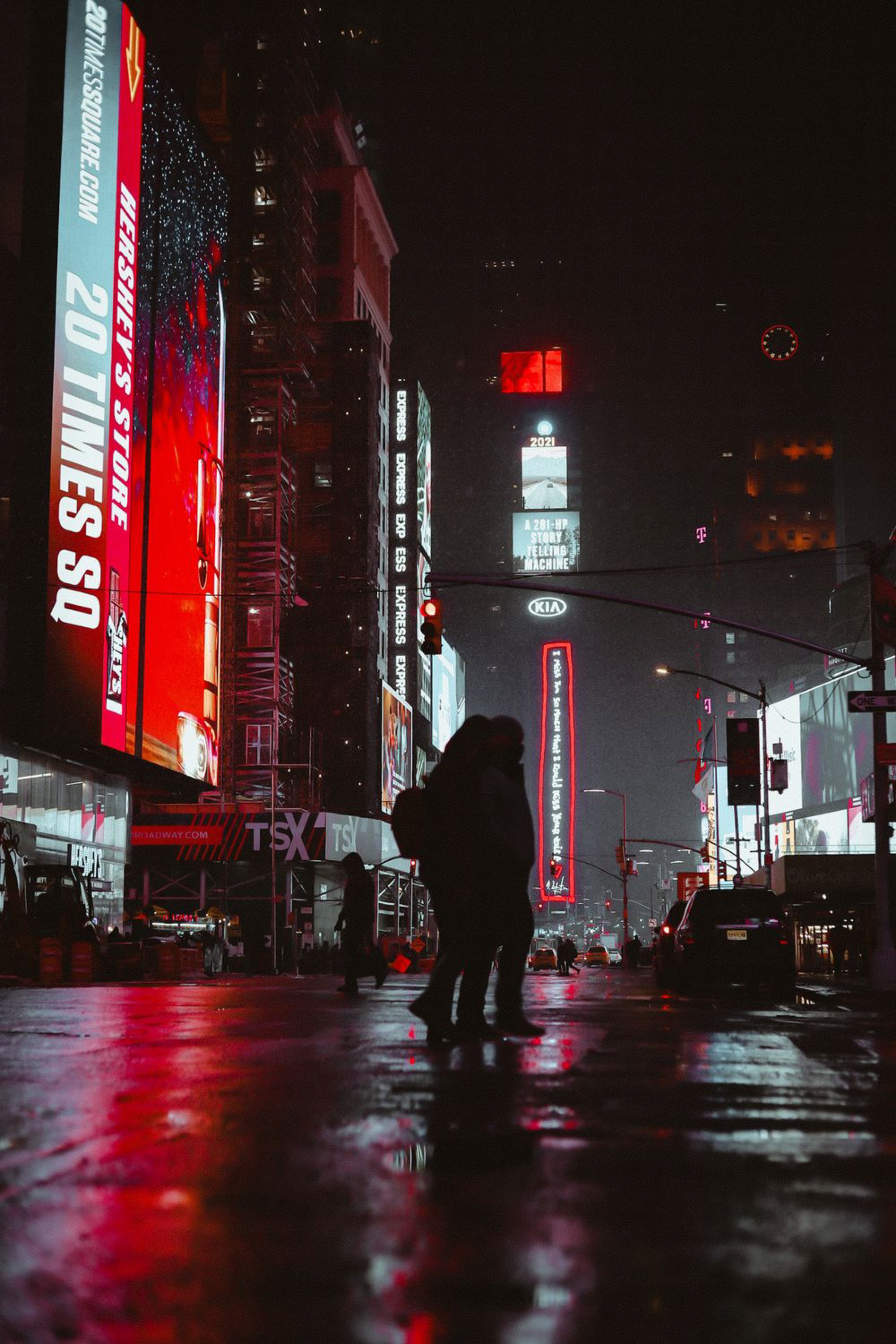 Silhouette against neon Times Square billboards on a rainy New York night