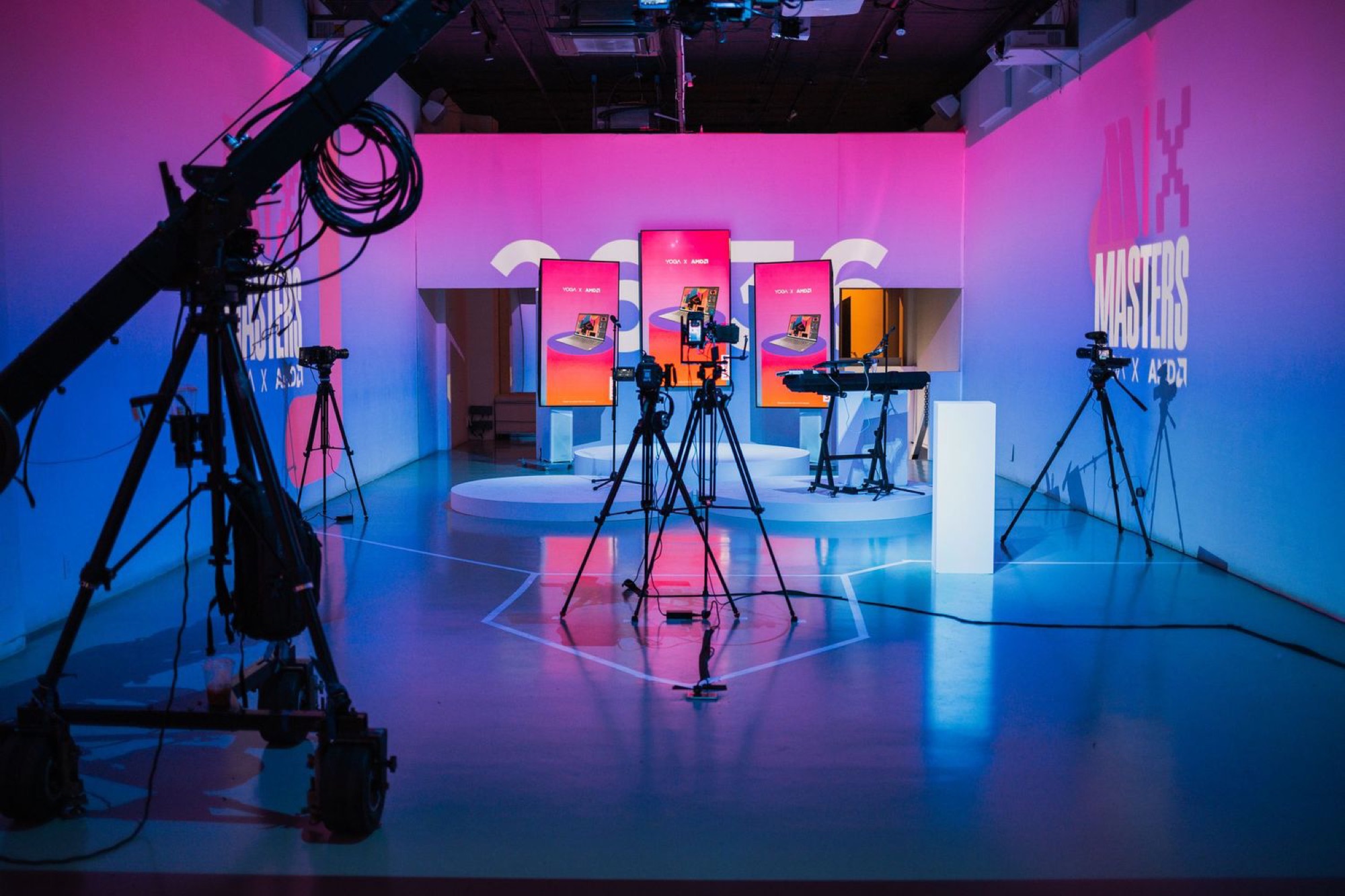 Empty studio production set for the Lenovo x AMD Masters shoot, with a camera jib, tripods, and lit monitor displays arranged before the crew arrives