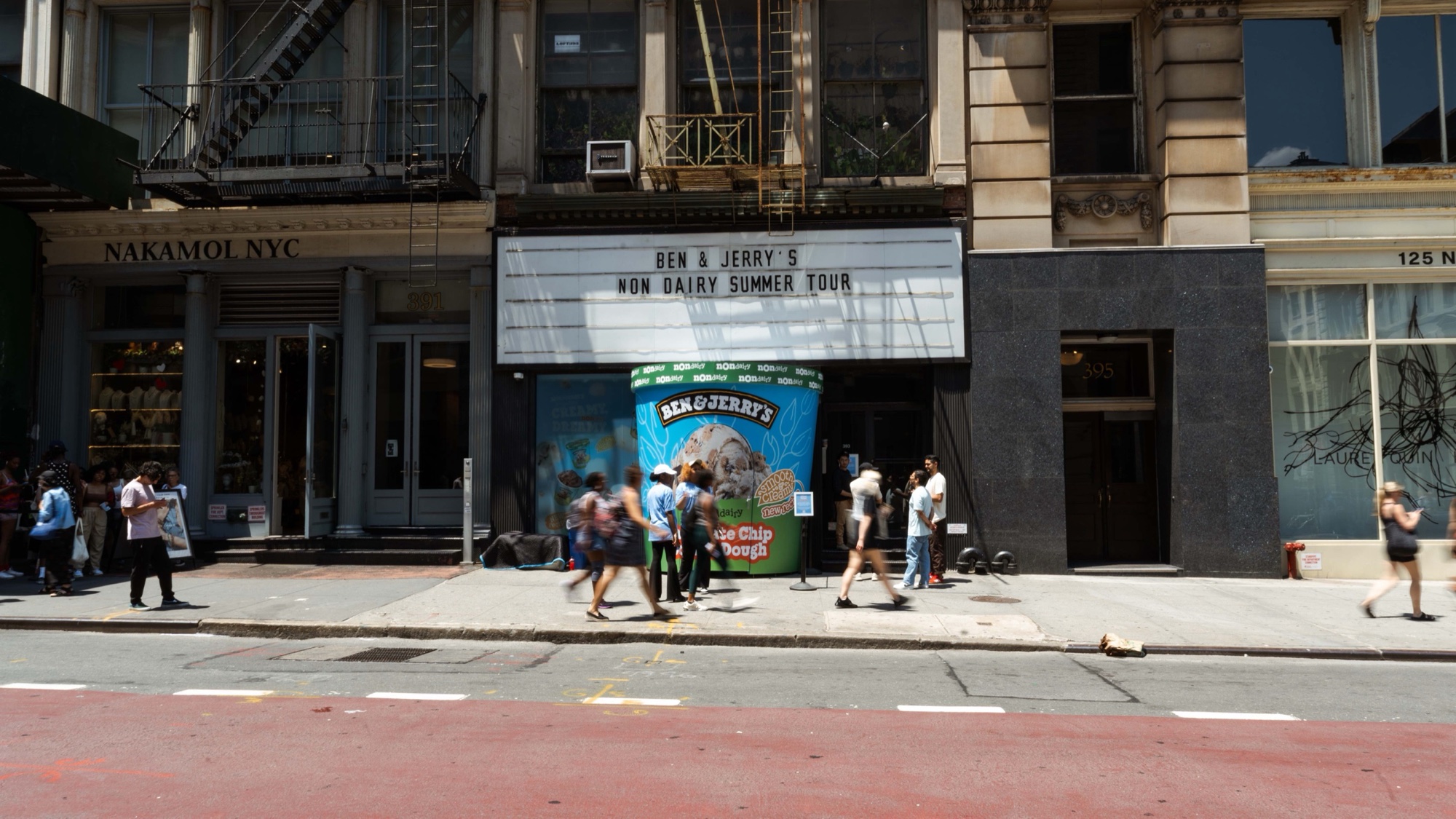 A Ben & Jerry’s Non-Dairy Summer Tour marquee above a storefront on a sunny New York street