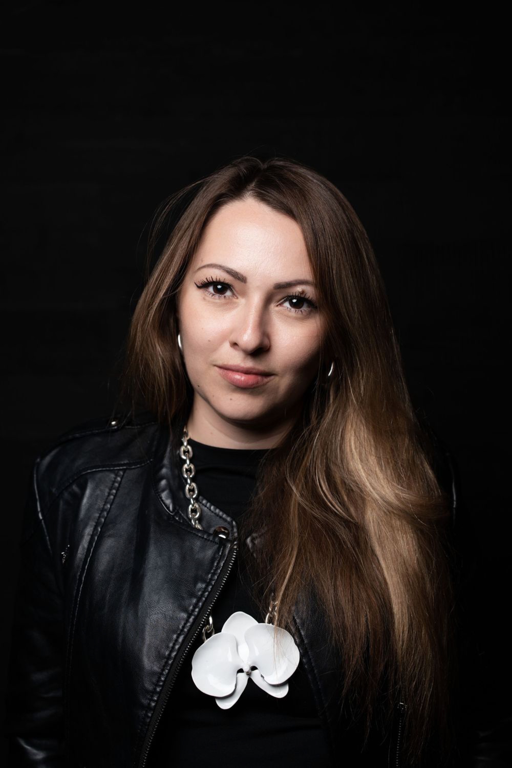 Studio portrait series of a person with long brown hair in a black leather jacket on a dark background