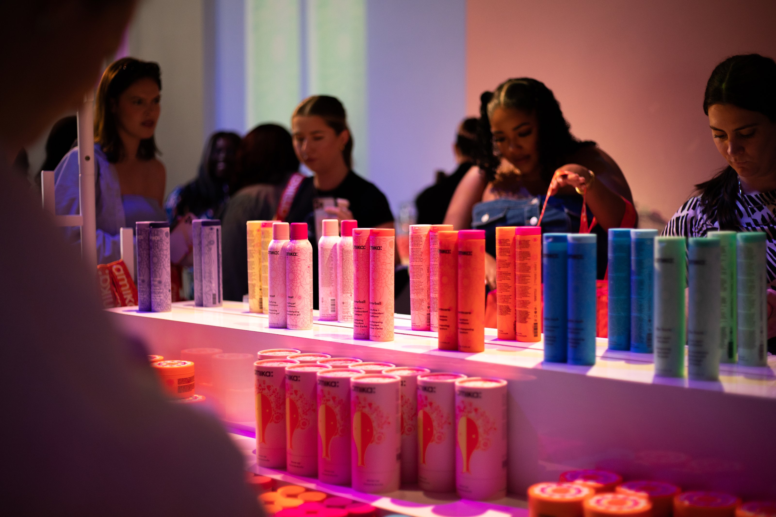Guests browse colorful bottles of hair products on a white display counter during the Amika event at Lume Studios in Tribeca, Manhattan.