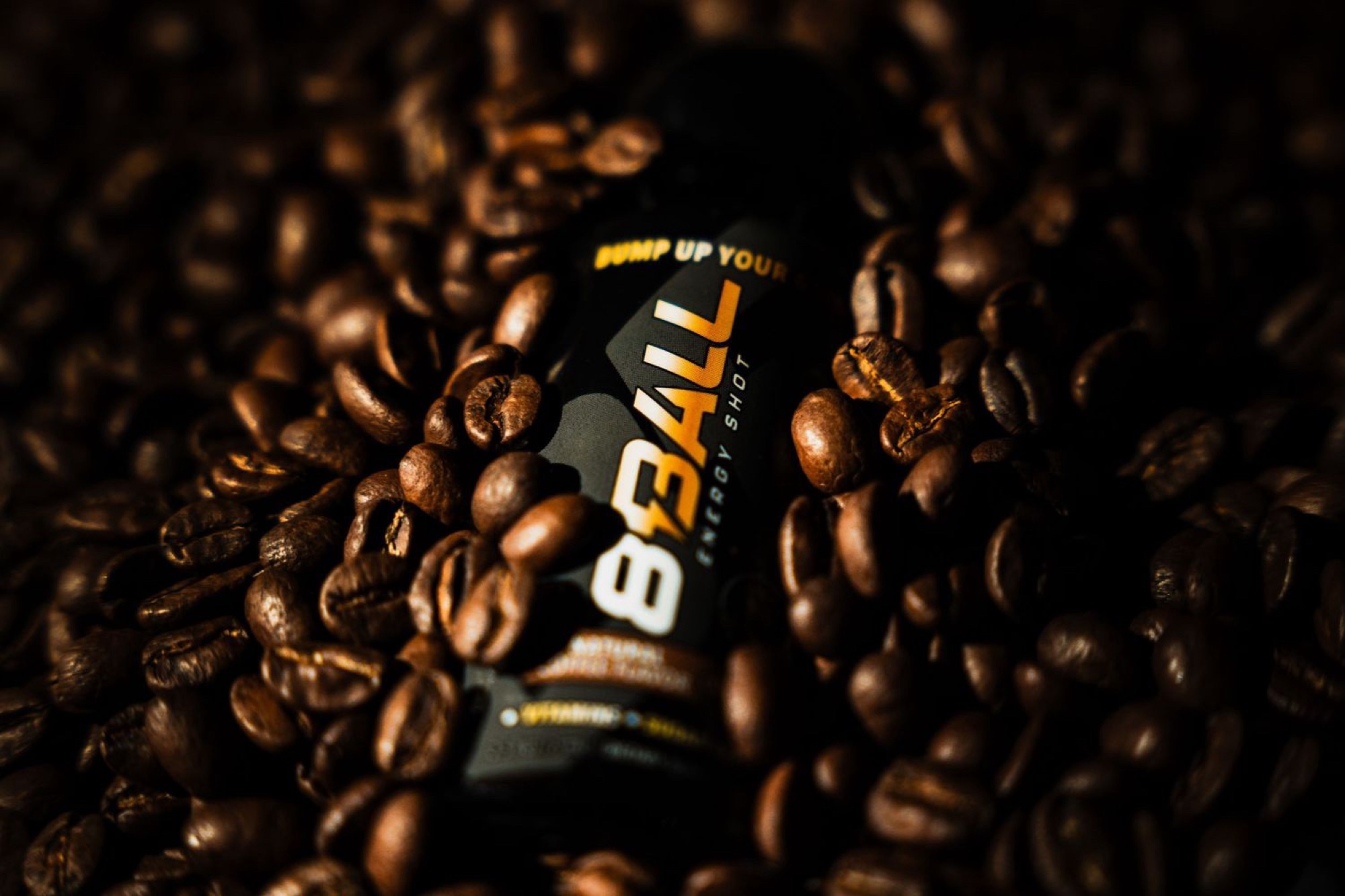 8Ball Energy shot nestled in a bed of roasted coffee beans lit by warm directional light