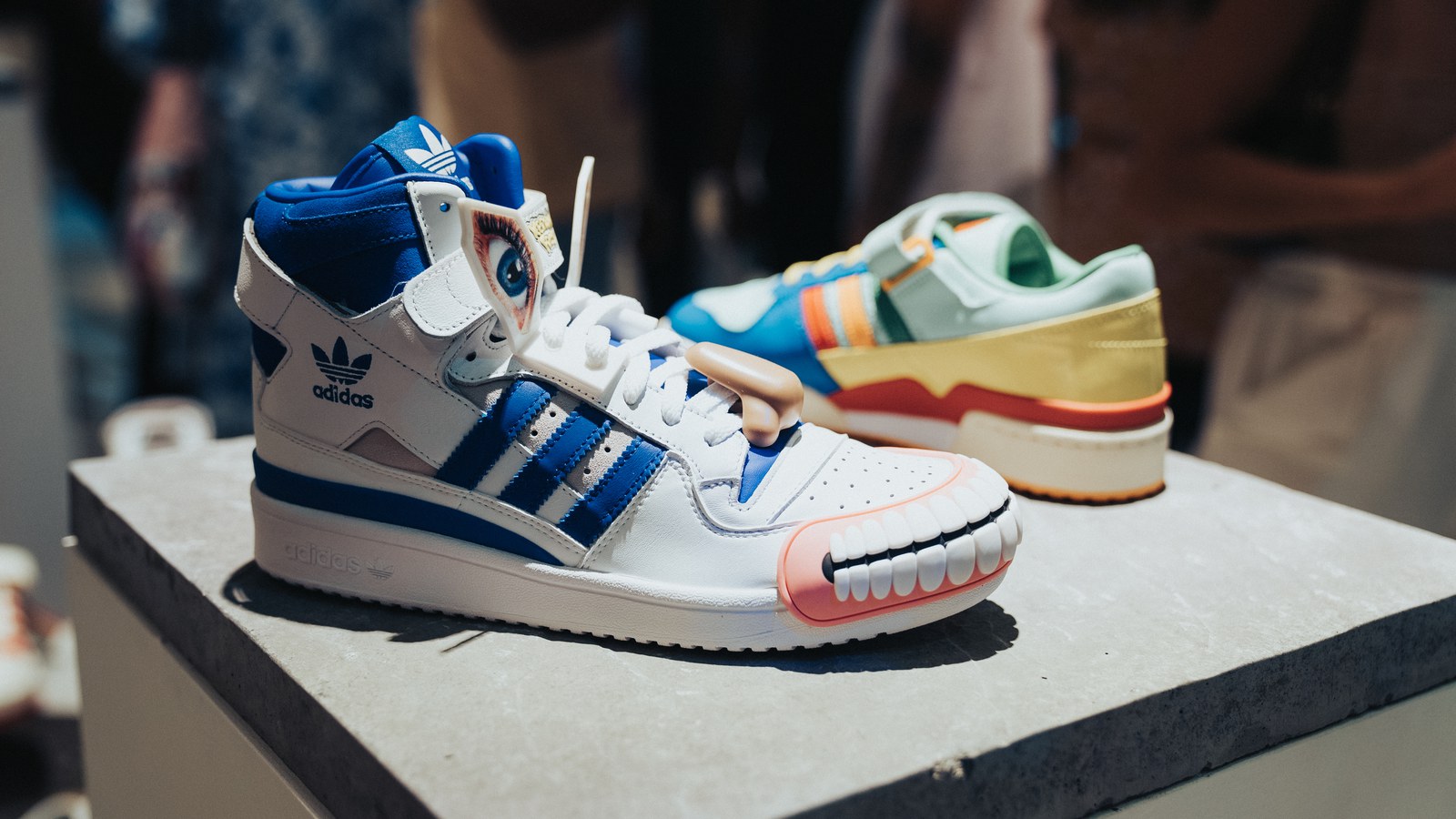 Visitor walks through an Adidas Originals basketball gallery with hanging Forum sneakers and framed artwork