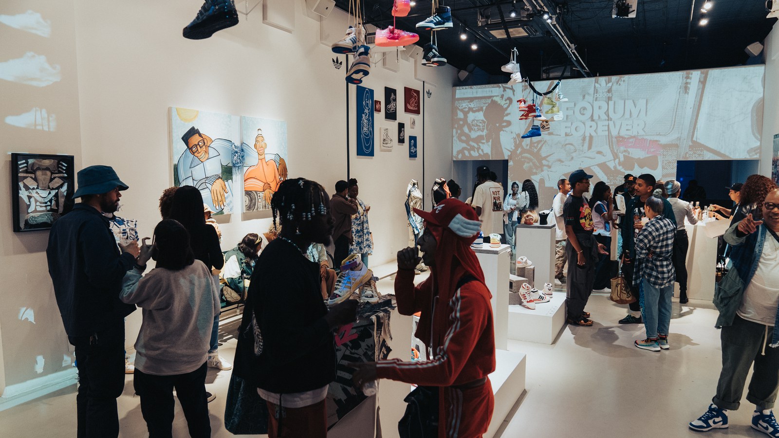 Guests browse a white gallery with sneakers hung from the ceiling and a Forum Forever projection on the far wall