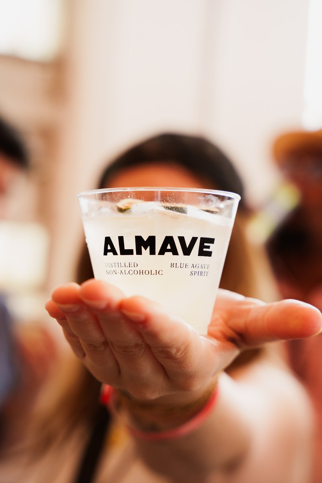 Hand offers an Almave blue agave tasting cup toward the camera at the New York event