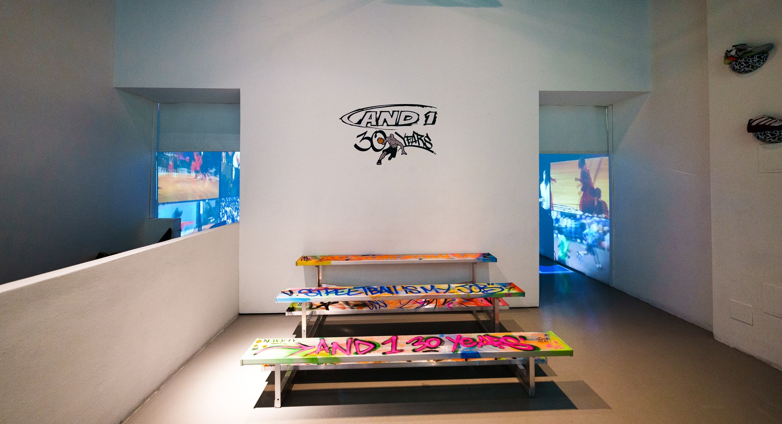 Graffiti painted benches in front of a white wall with an AND1 30 years logo