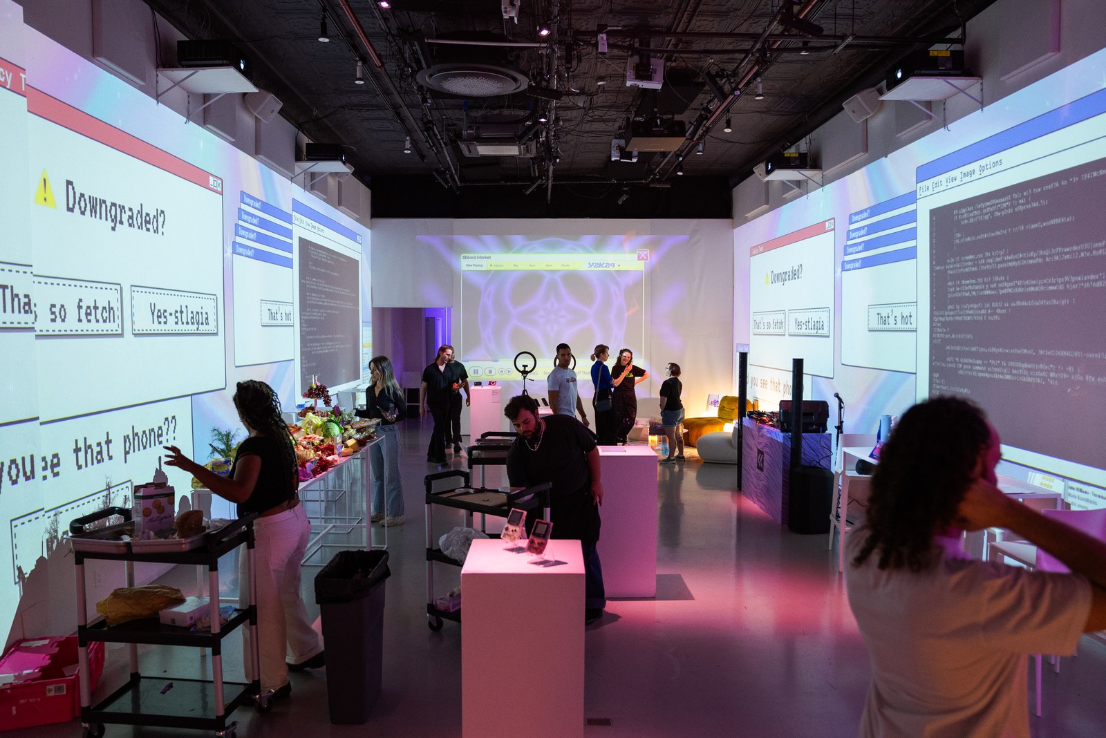 Guests mingle in a white room with retro computer dialog boxes projected on the walls