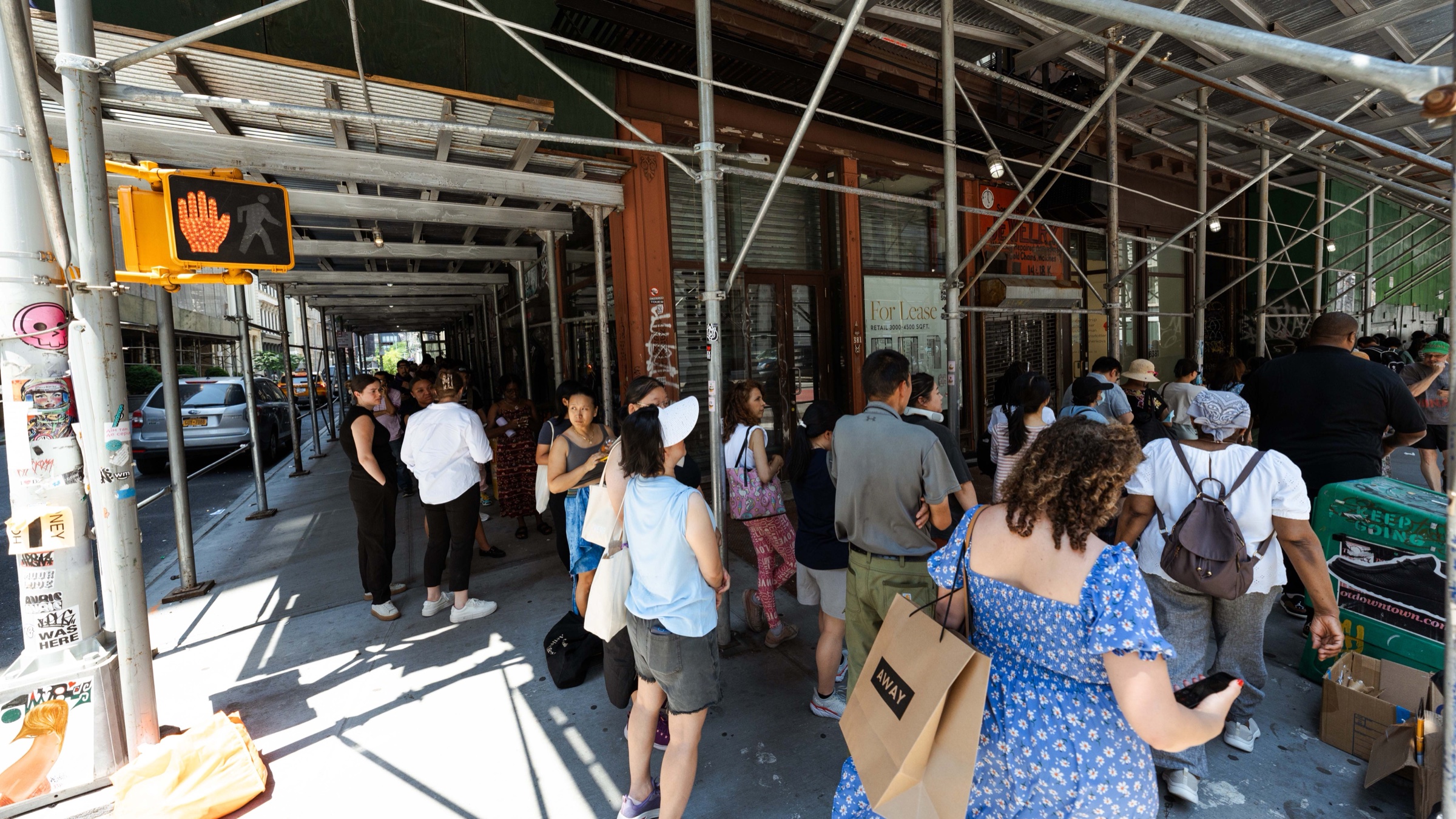 Visitors form a long line under sidewalk scaffolding for Ben & Jerry’s Non-Dairy popup in New York
