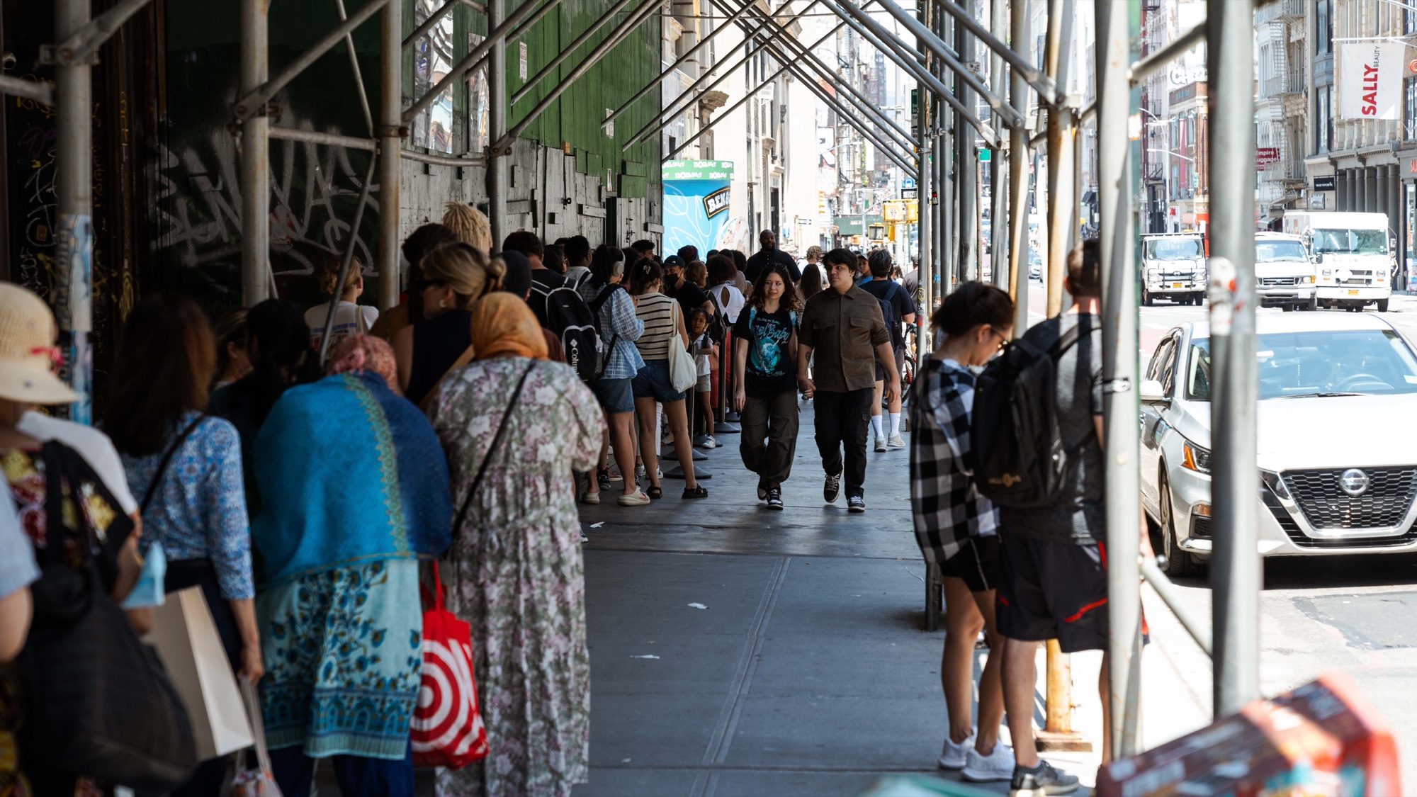 Crowd queuing beneath scaffolding on a city sidewalk near the Ben & Jerry’s activation entrance