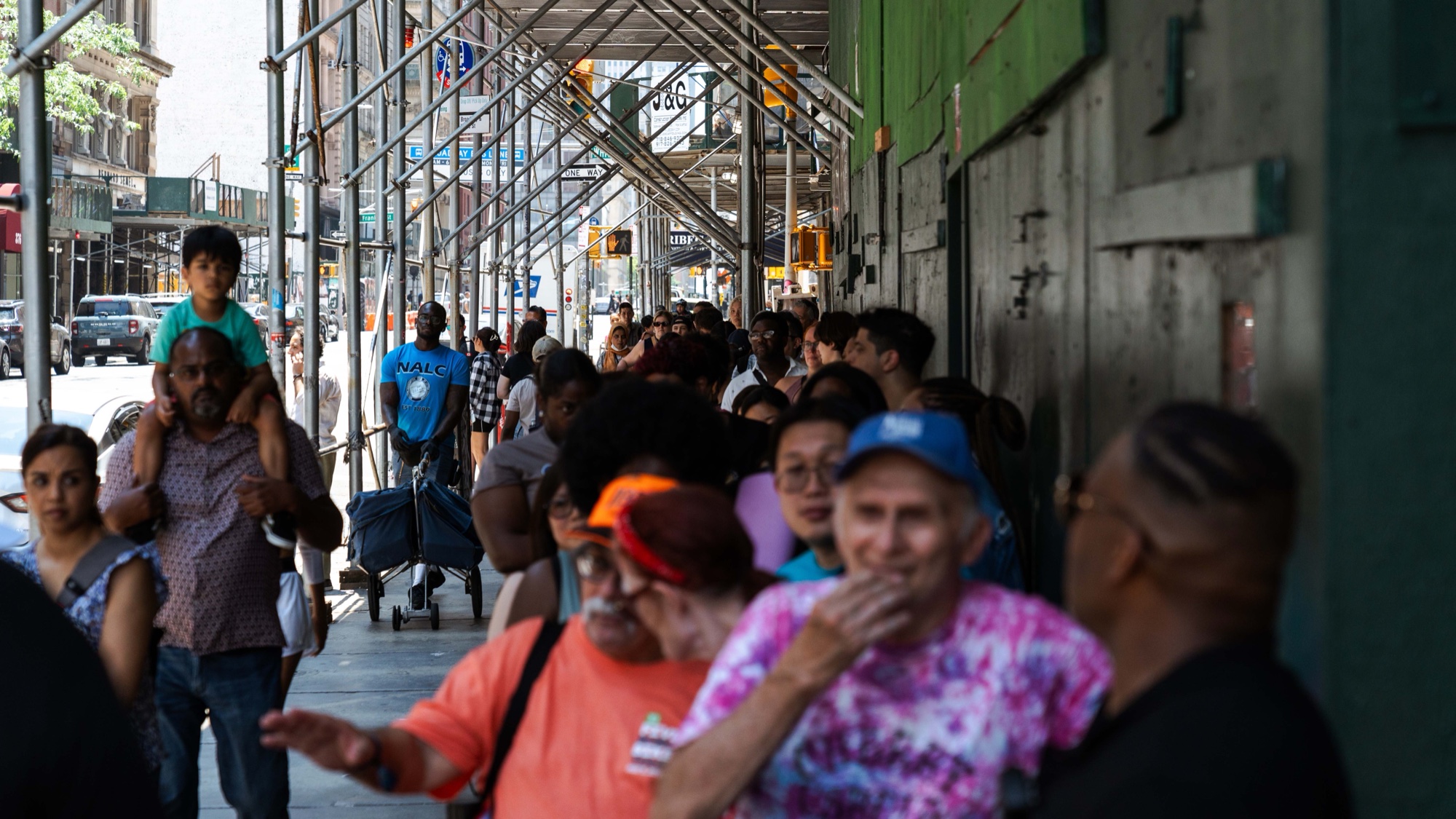 Sunlit sidewalk packed with people of all ages lining up for the Ben & Jerry’s summer event