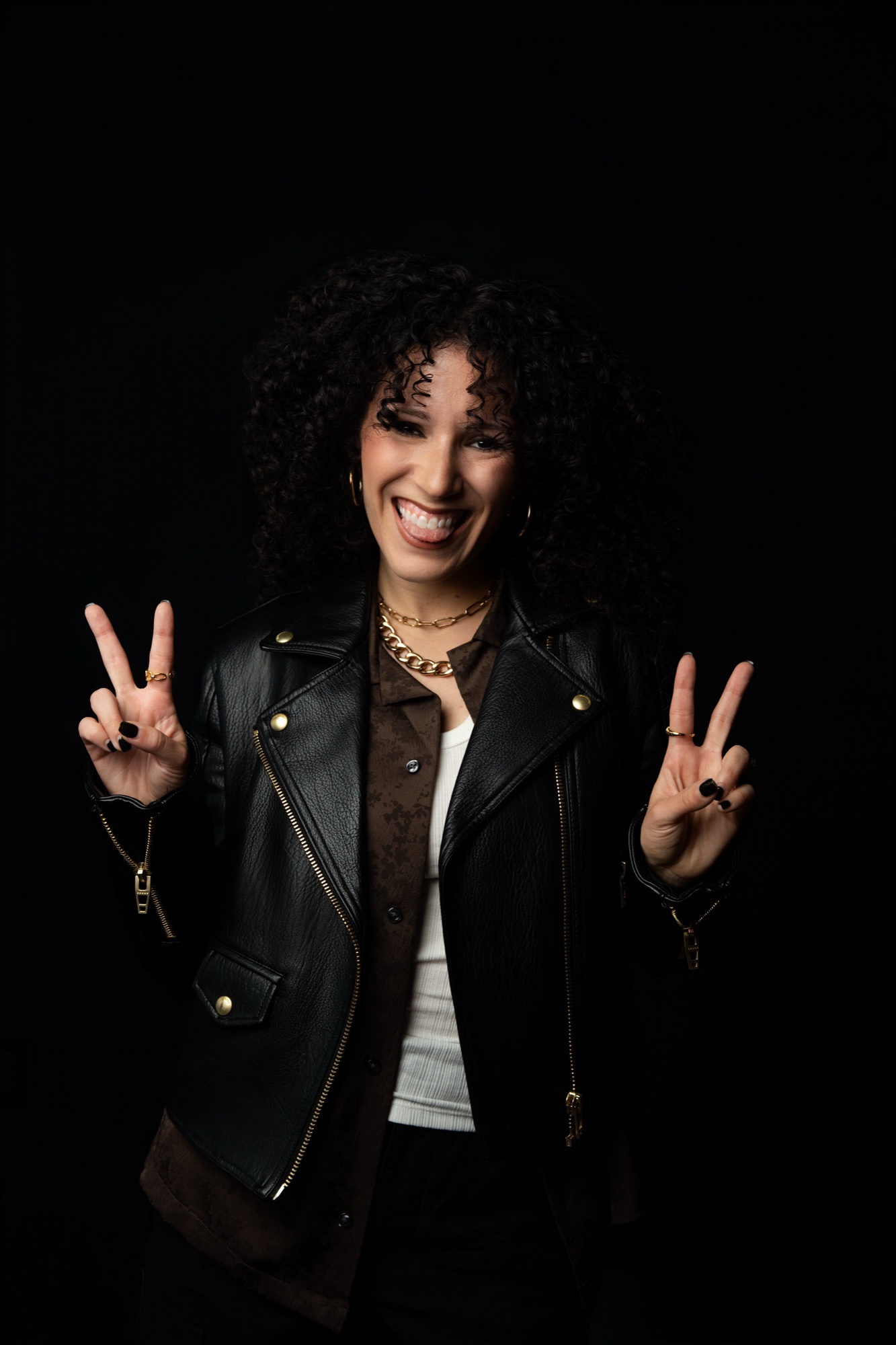 Ali Schwartz laughing in a black leather jacket, both hands raised in peace signs