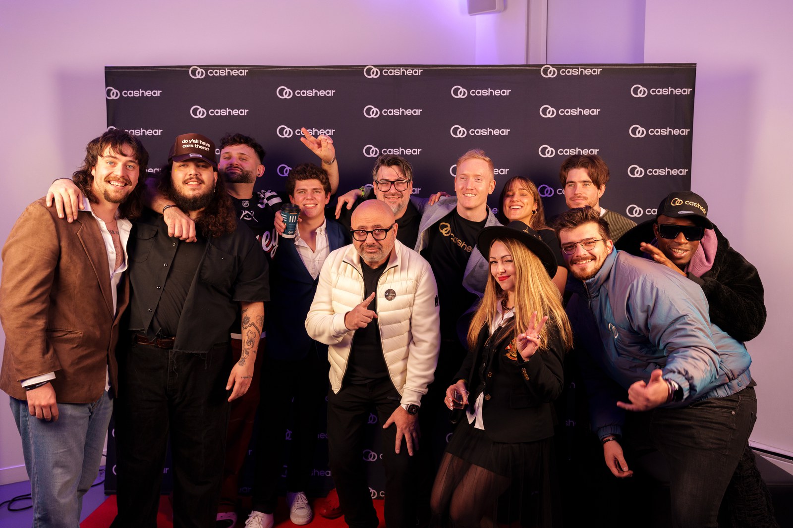 A large group pressed together posing on the Cashear step and repeat