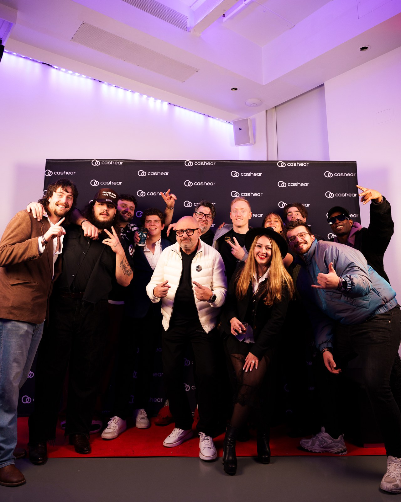 A group posing on the red carpet in front of the Cashear step and repeat