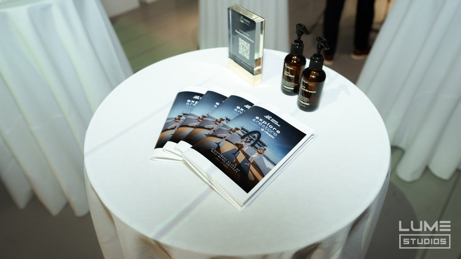 Round white table with fanned brochures, two amber pump bottles and a QR code card