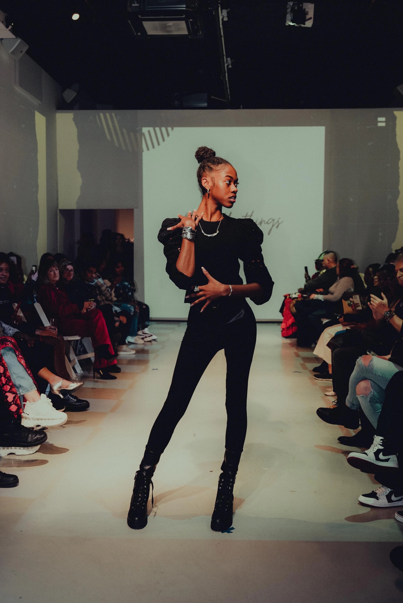 Model in a black jumpsuit and heeled boots opens the DigitalAX show before a projected backdrop