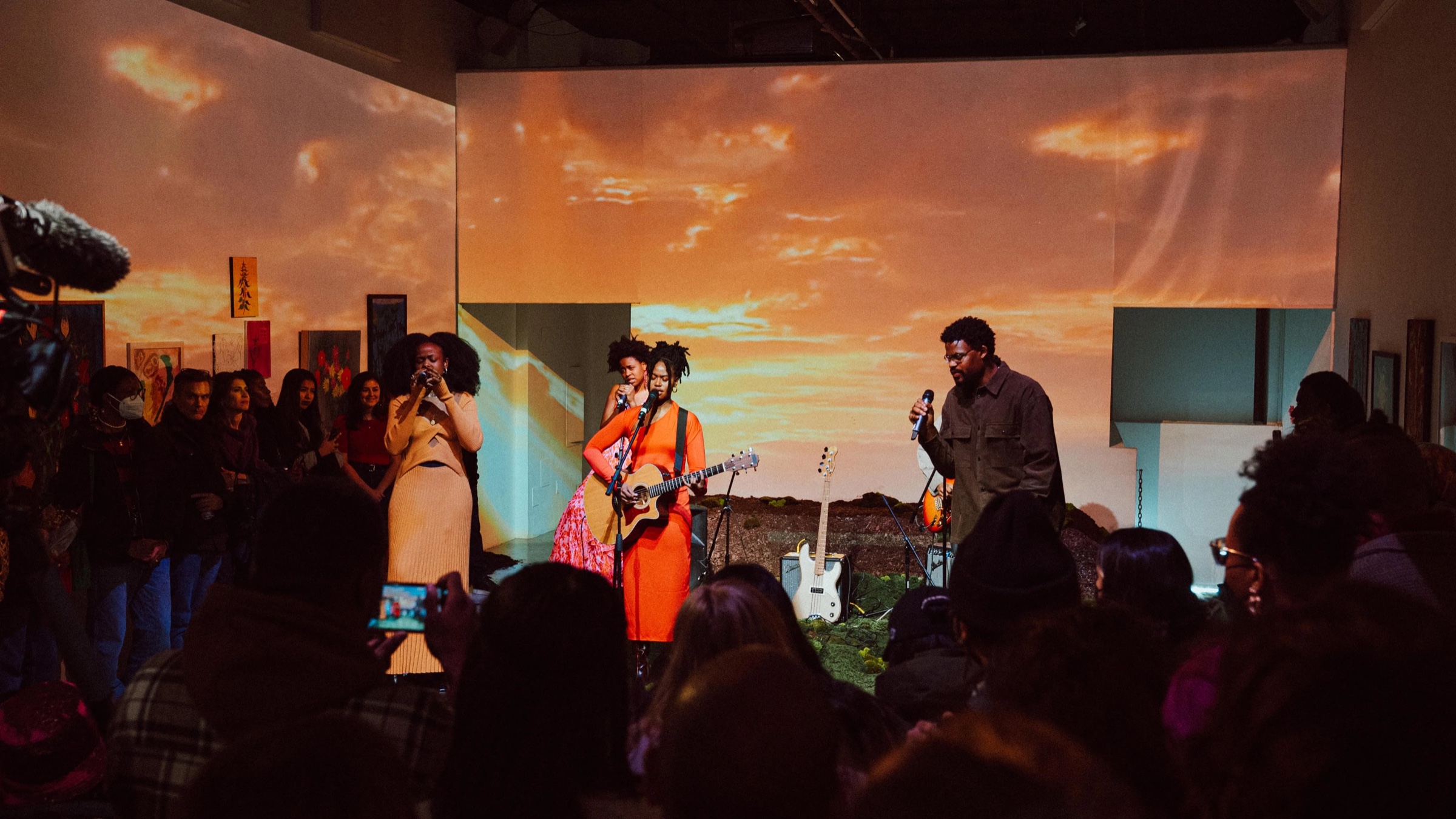 Infinity Song performs in front of a projected sunset as the Dirty Flowers crowd films on phones