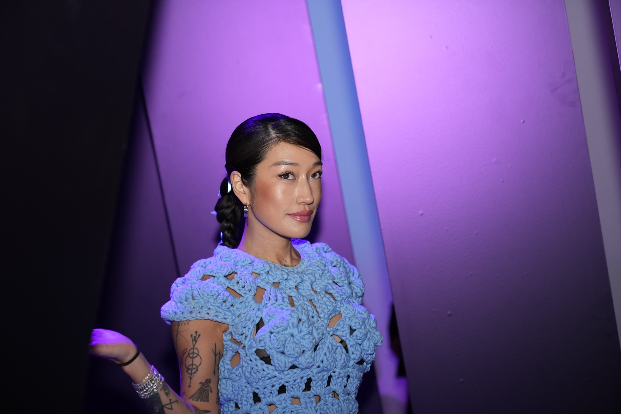 Peggy Gou poses in a blue crochet top against purple and blue panels at her Gouvenirs takeover