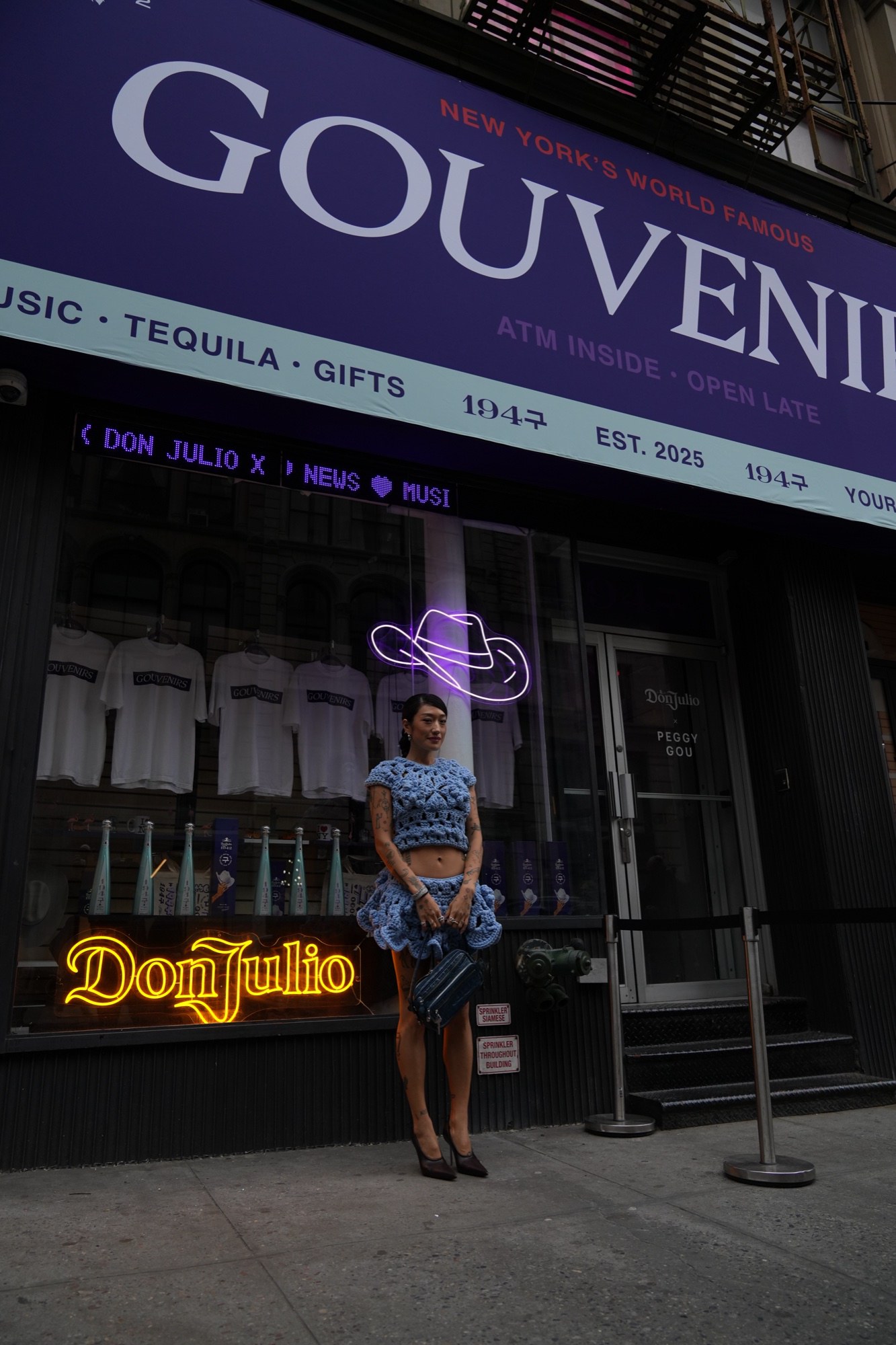 Sideways frame of a storefront with a Don Julio neon sign, a purple neon figure and a Gouvenirs banner