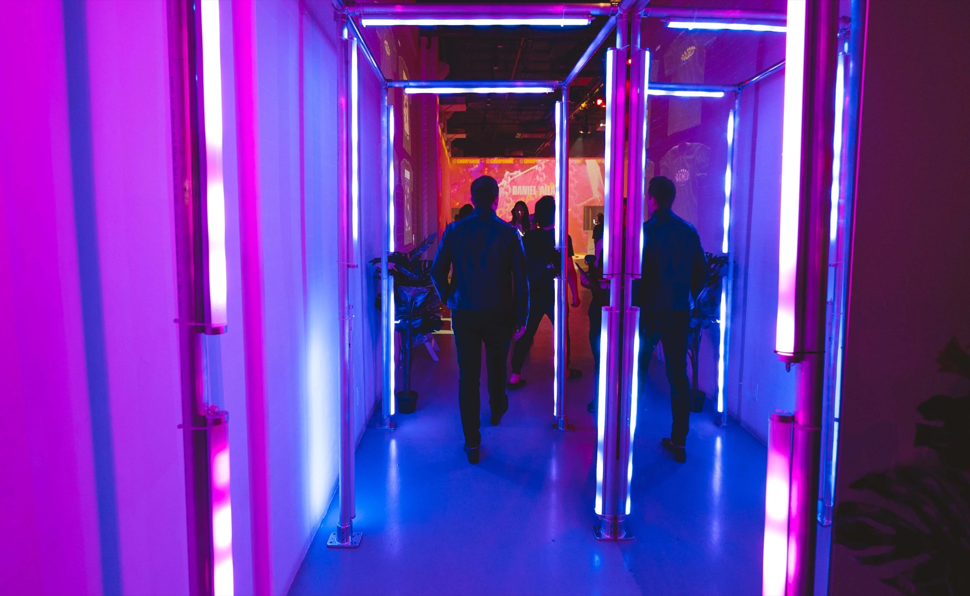 Guests pass through a corridor framed by pink and blue neon light bars at Dopamine