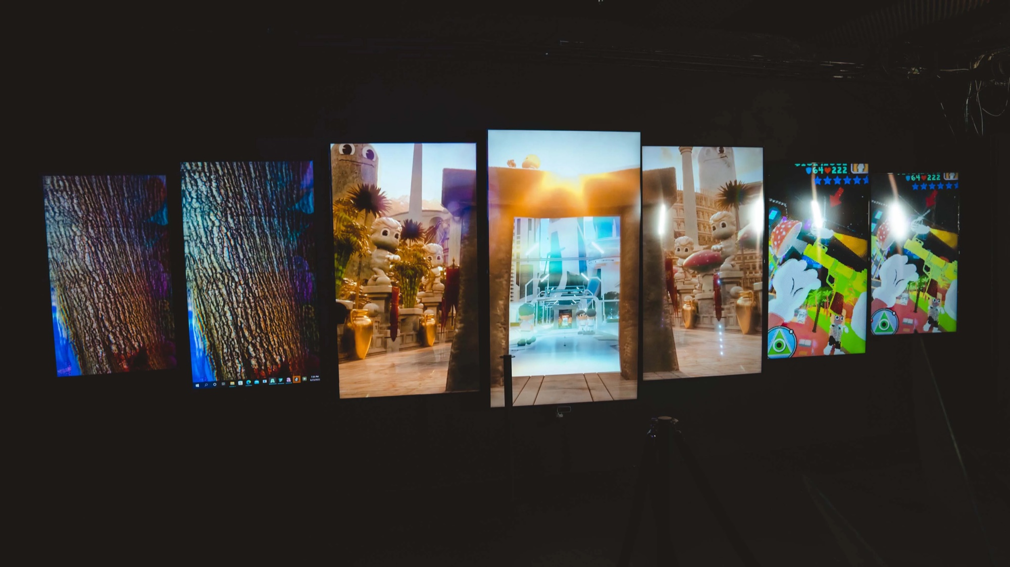 Row of tilted screens displaying digital artworks in the dark at the Dopamine NFT NYC event