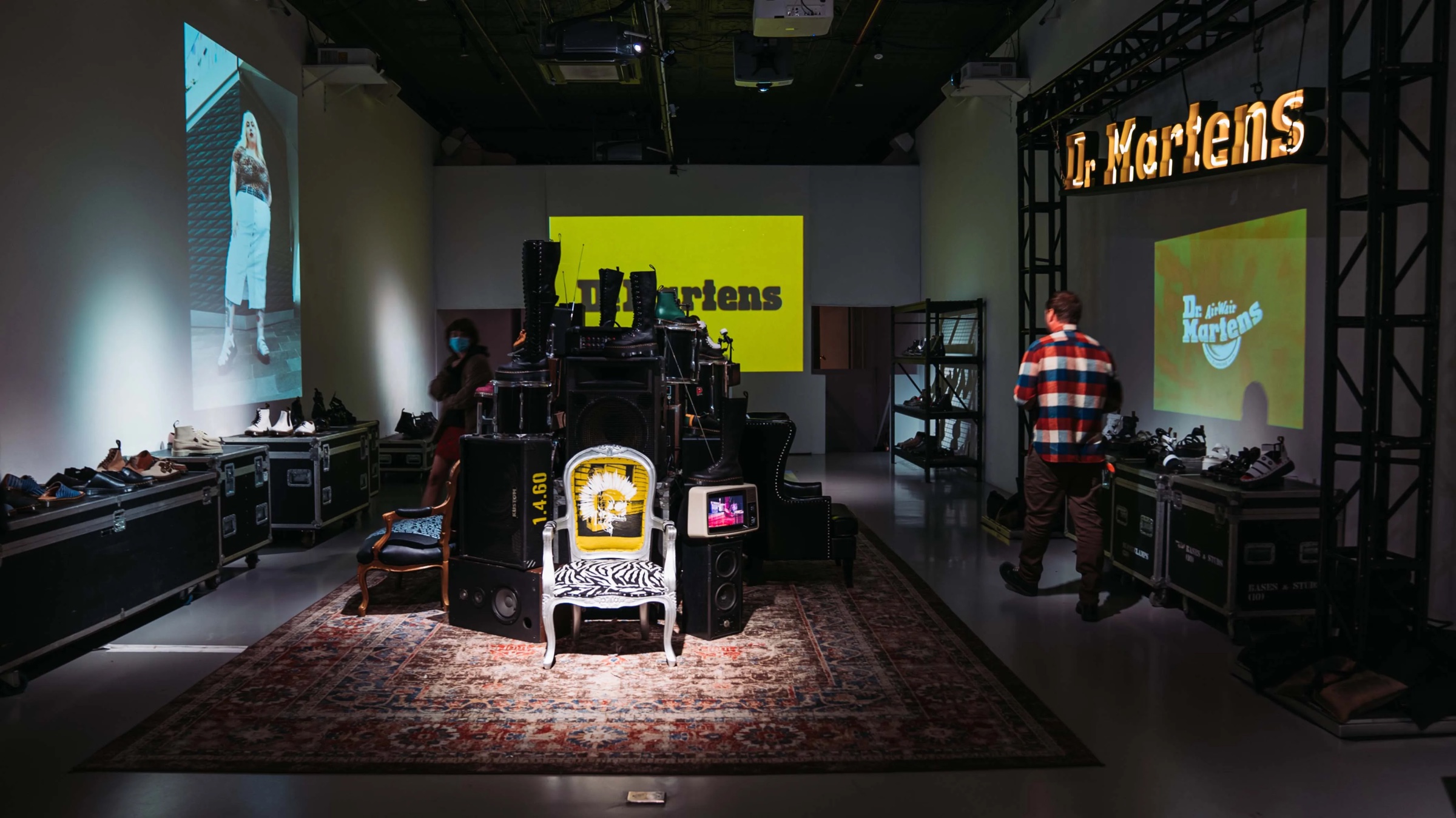 Dr. Martens installation with road cases, a speaker tower on a rug and projected boots at Lume Studios