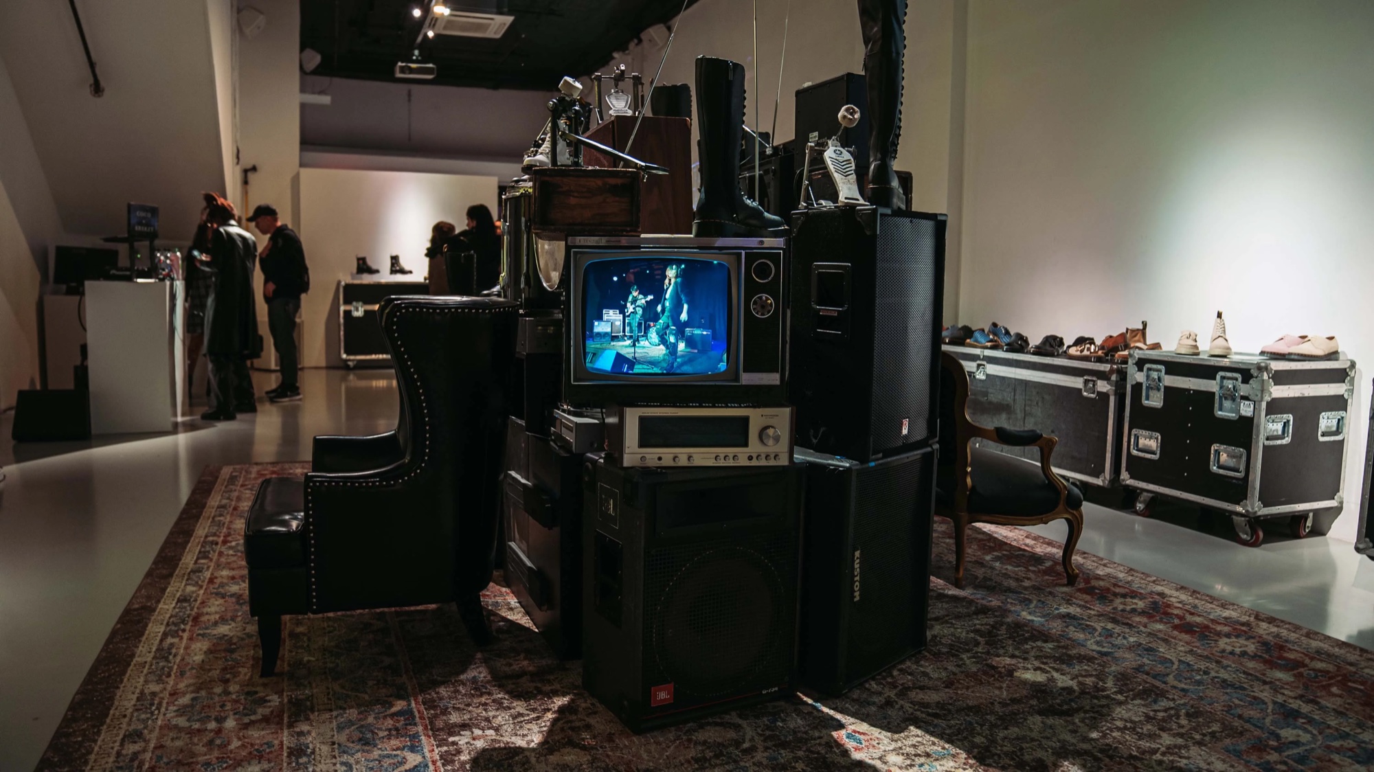 Stacked vintage speakers and a television flank a wingback chair on a Persian rug at the Dr. Martens event