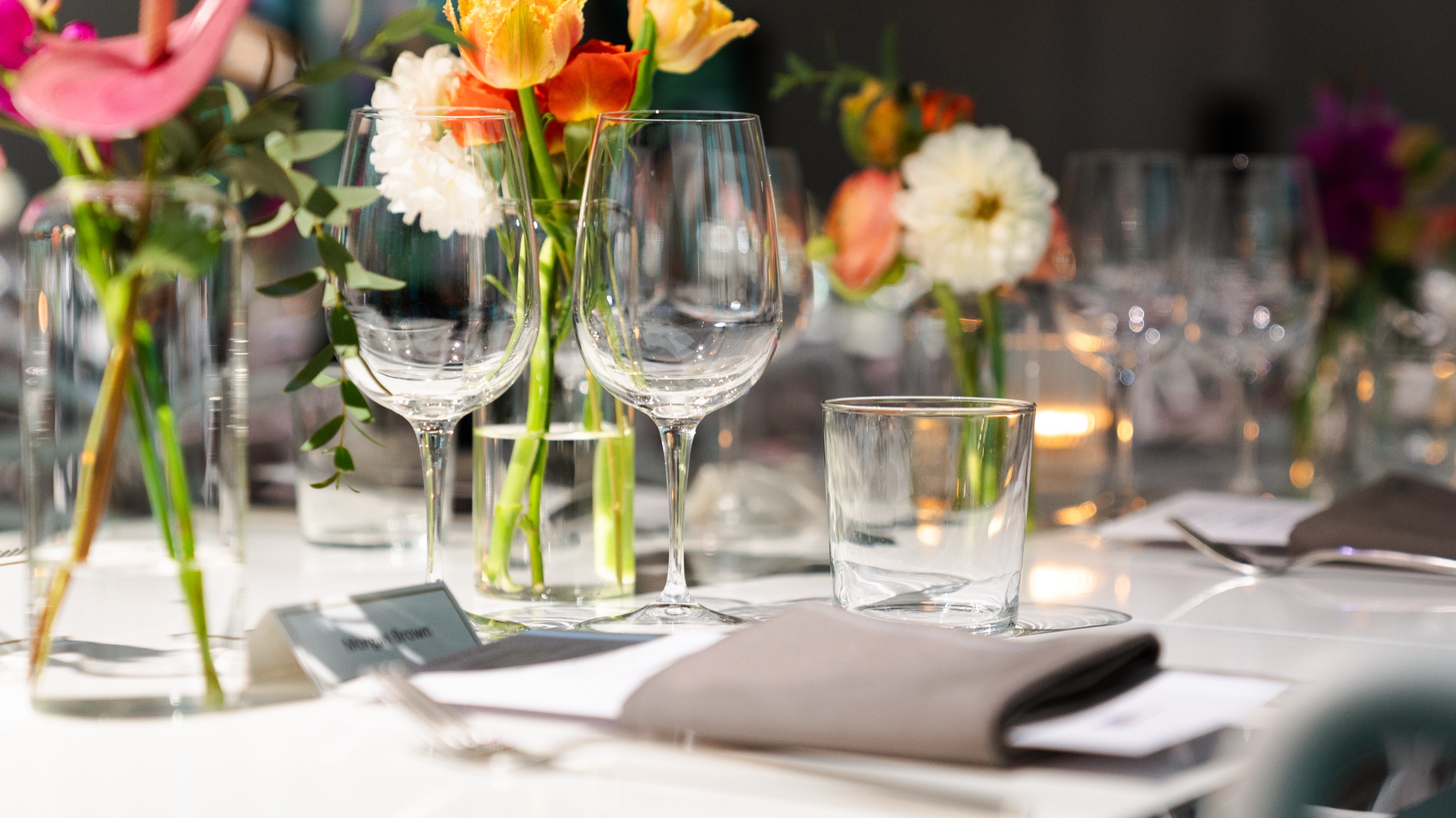Diner finishes a plated course beside red wine and tulips at the Dropbox showcase