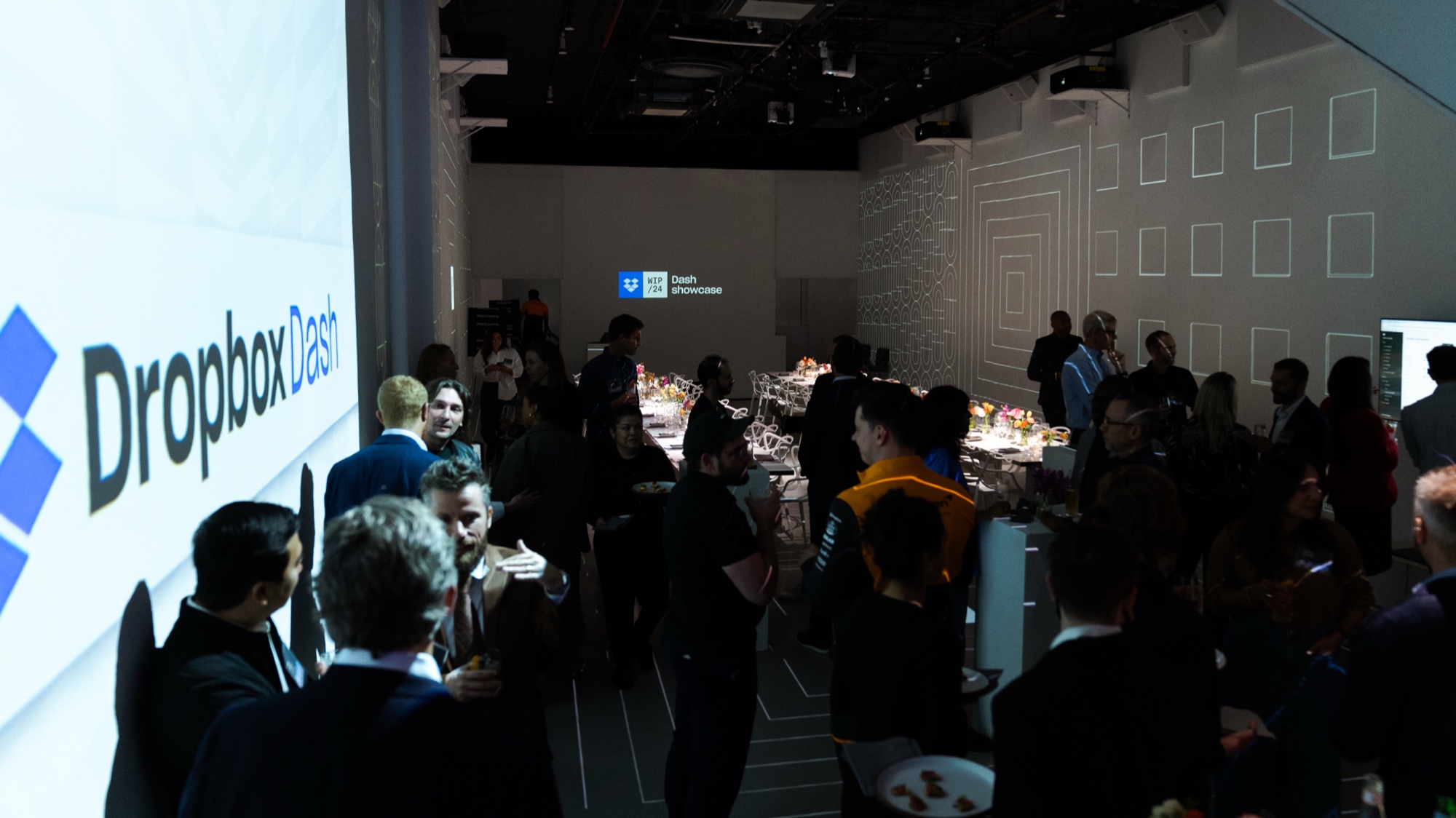 Wide view of the Dropbox dinner with city projections and white designer chairs