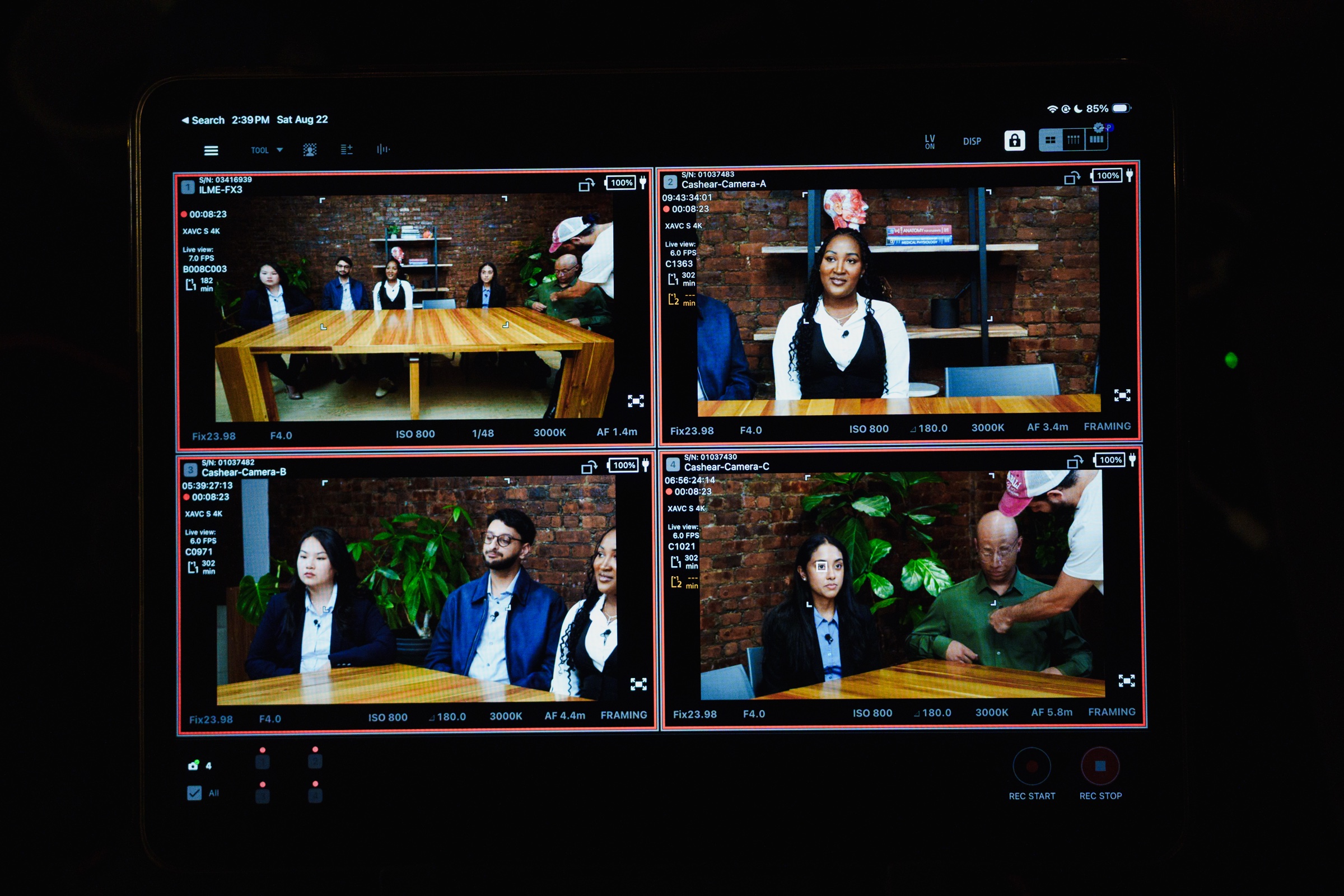 Monitor screen splits into four camera feeds showing the seated guests at the table from different angles