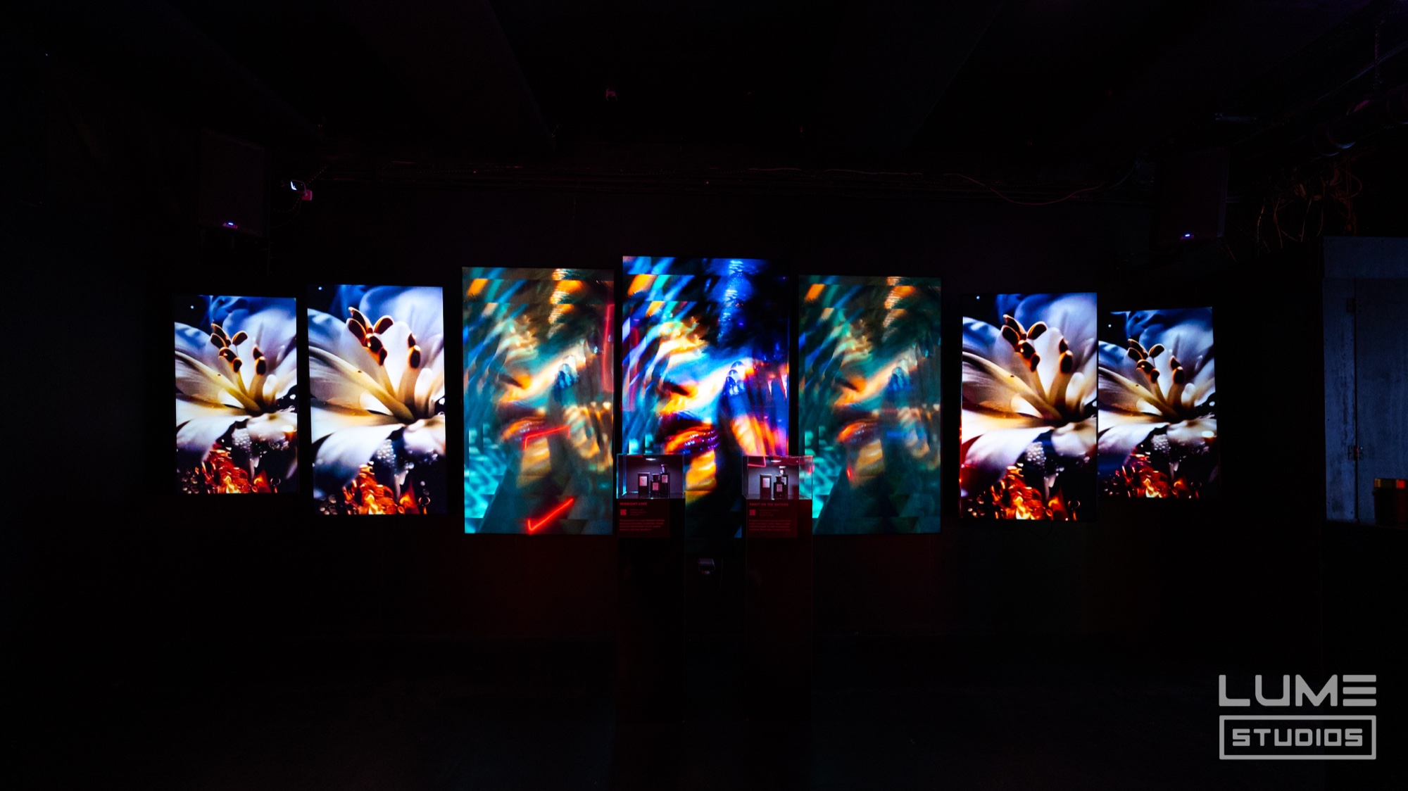 Greek island scene projected in blue behind white pedestals at the Fine’ry activation