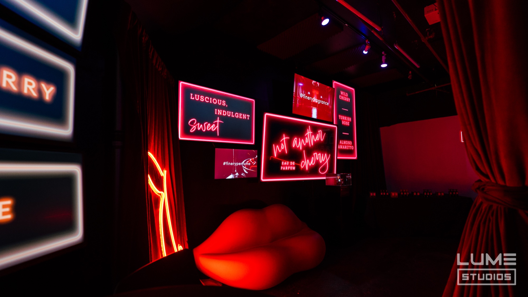 Red lip shaped sofa beneath pink neon signs reading not another cherry and luscious indulgent sweet