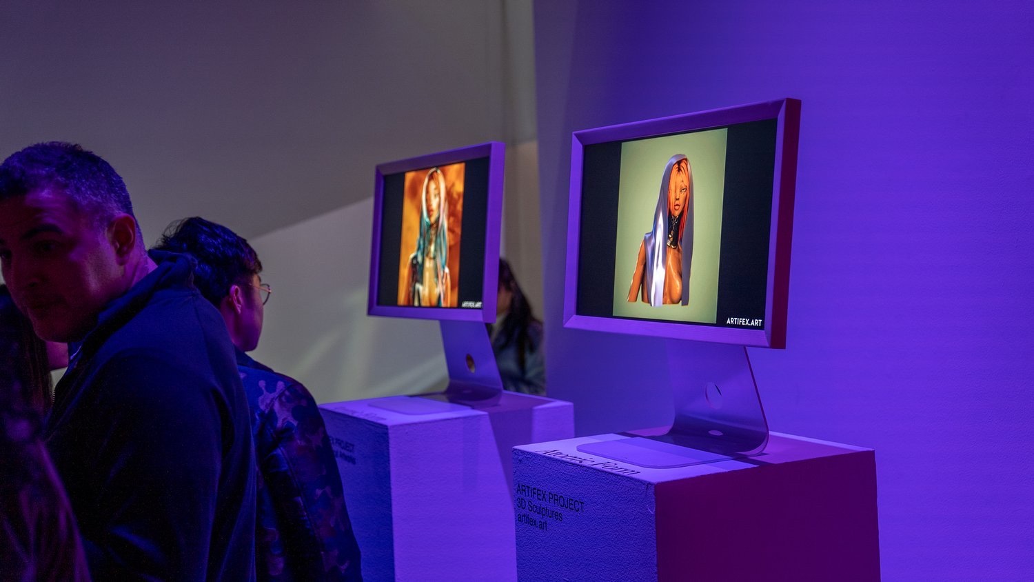 Guests view digital art on monitors bathed in purple light at the Hypebeast x Coinbase NFT gallery
