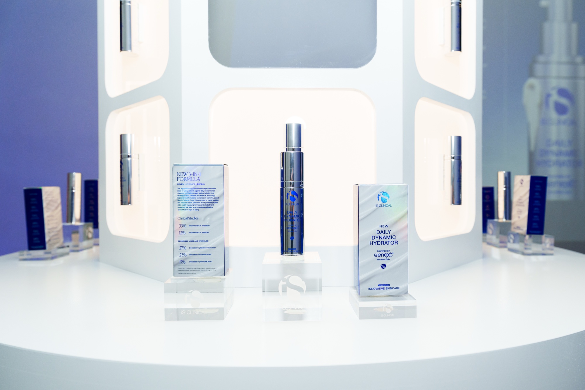 Serum bottle and product boxes displayed on clear risers in front of a lit white panel wall