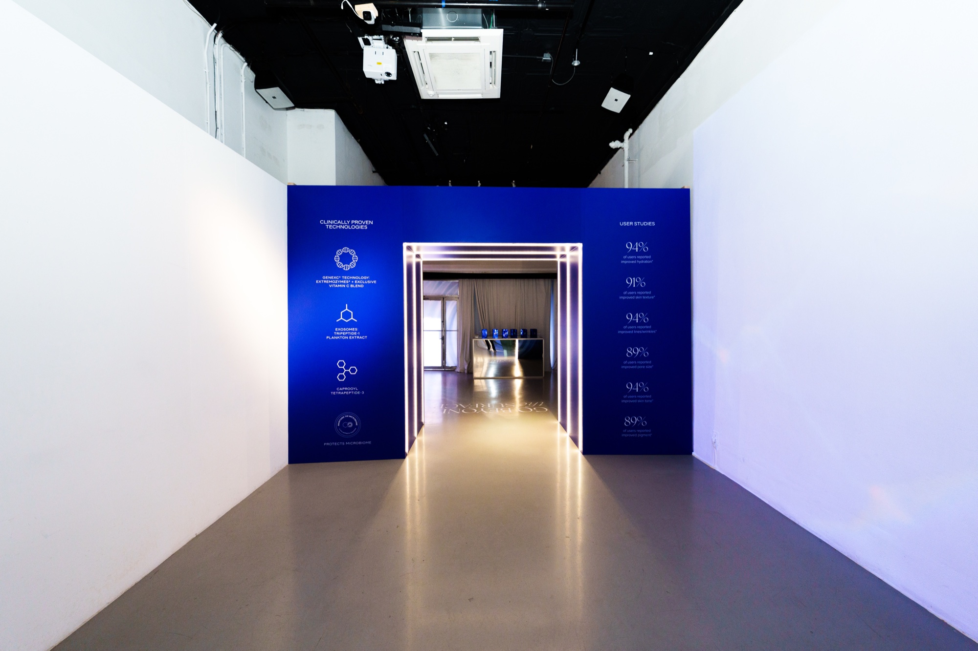 Dark blue gateway with printed icons and percentages set in a white gallery, leading to a lit corridor