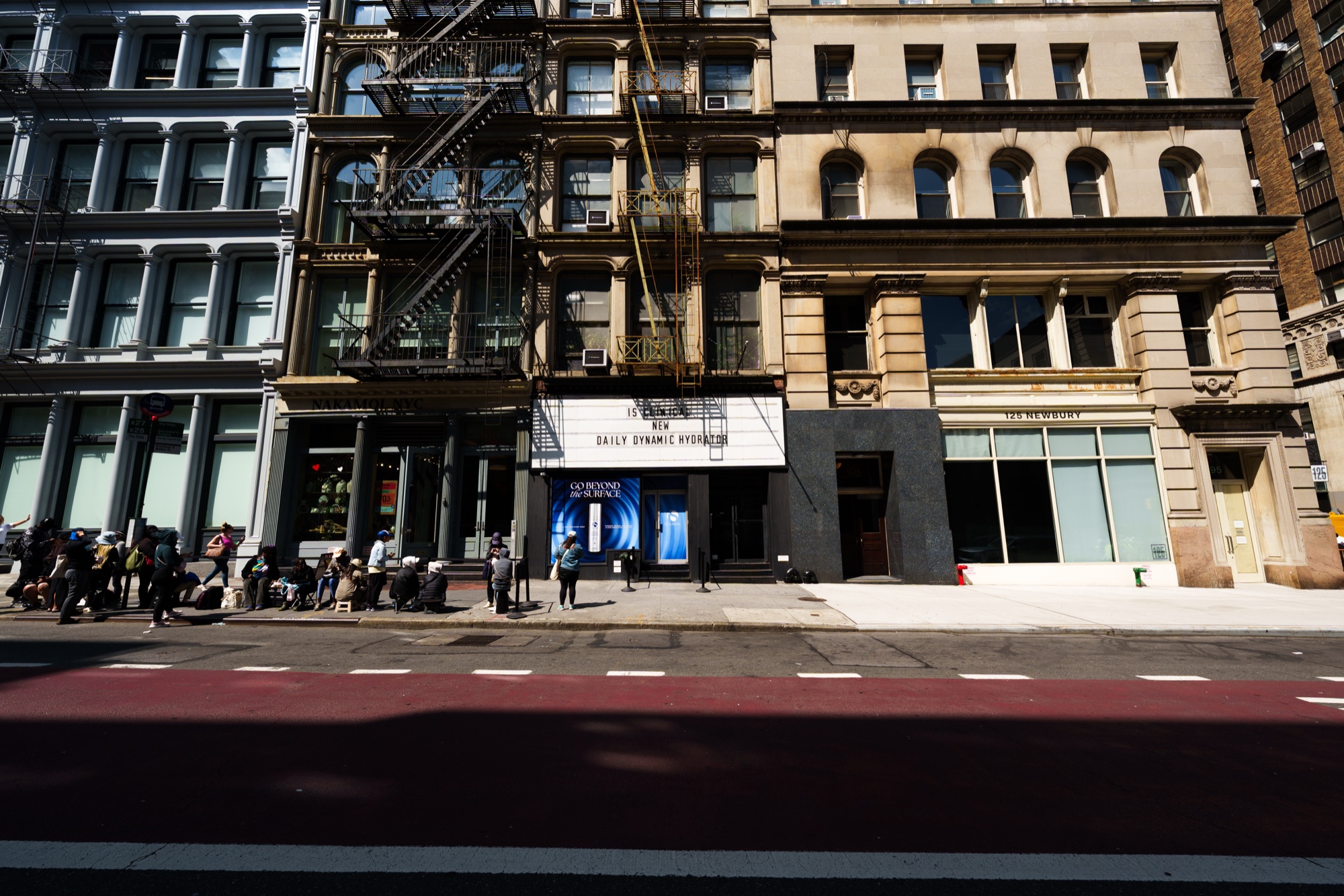 Sunlit street with a marquee reading iS Clinical New Daily Dynamic Hydrator on a cast iron building