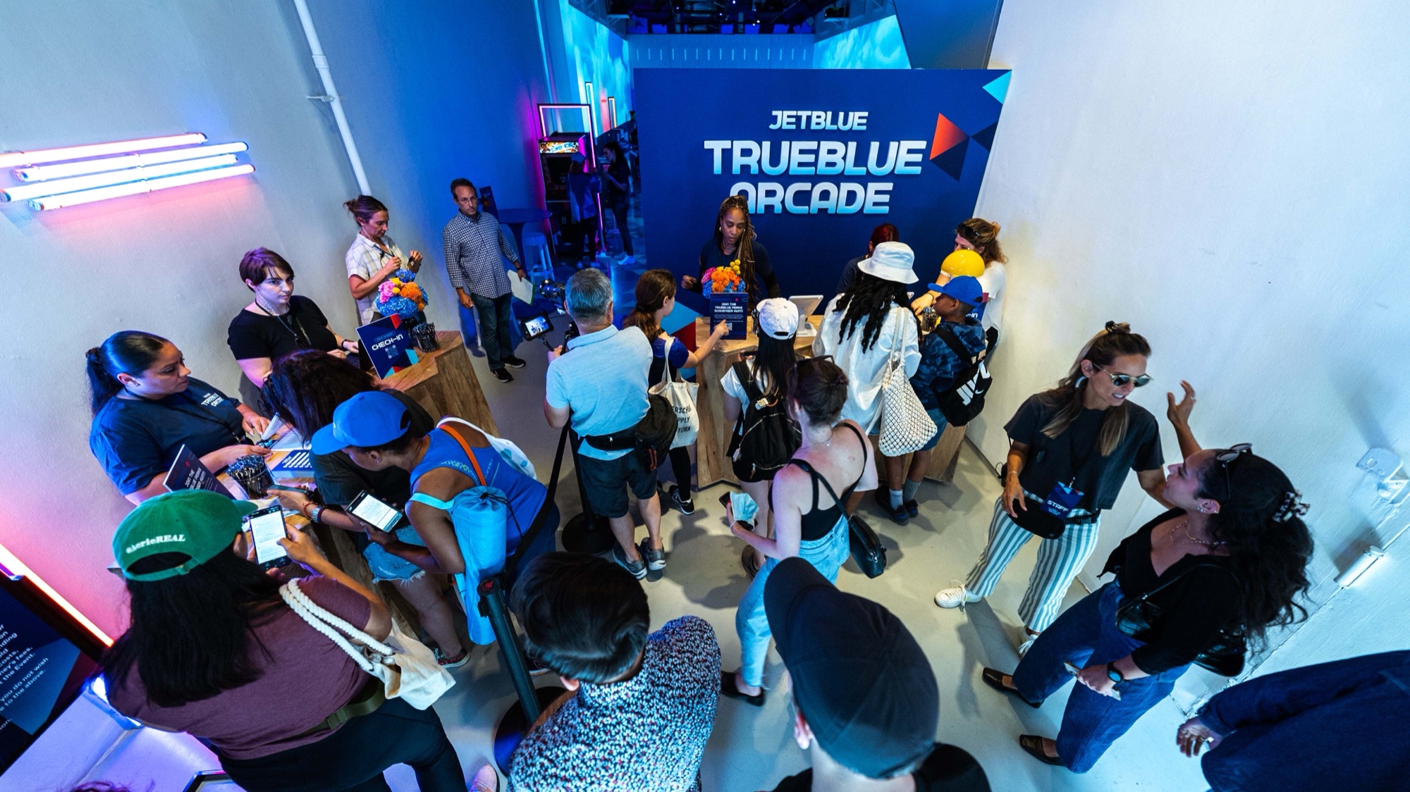 Player rolls a ball up the skee ball lane beneath a huge JetBlue TrueBlue projection