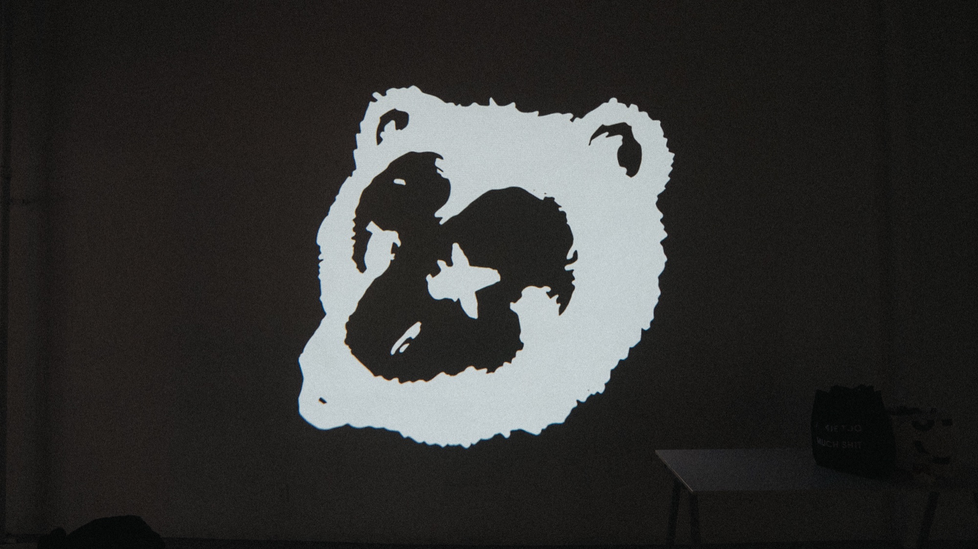 White bear face graphic with a star on its forehead projected onto a dark wall