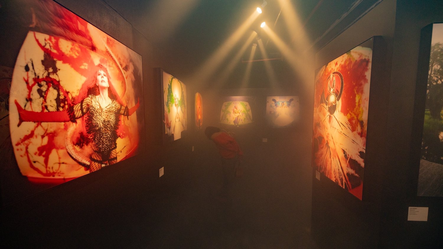 Vivid portraits glow through haze under warm spotlights at the Jordan Milligan exhibition