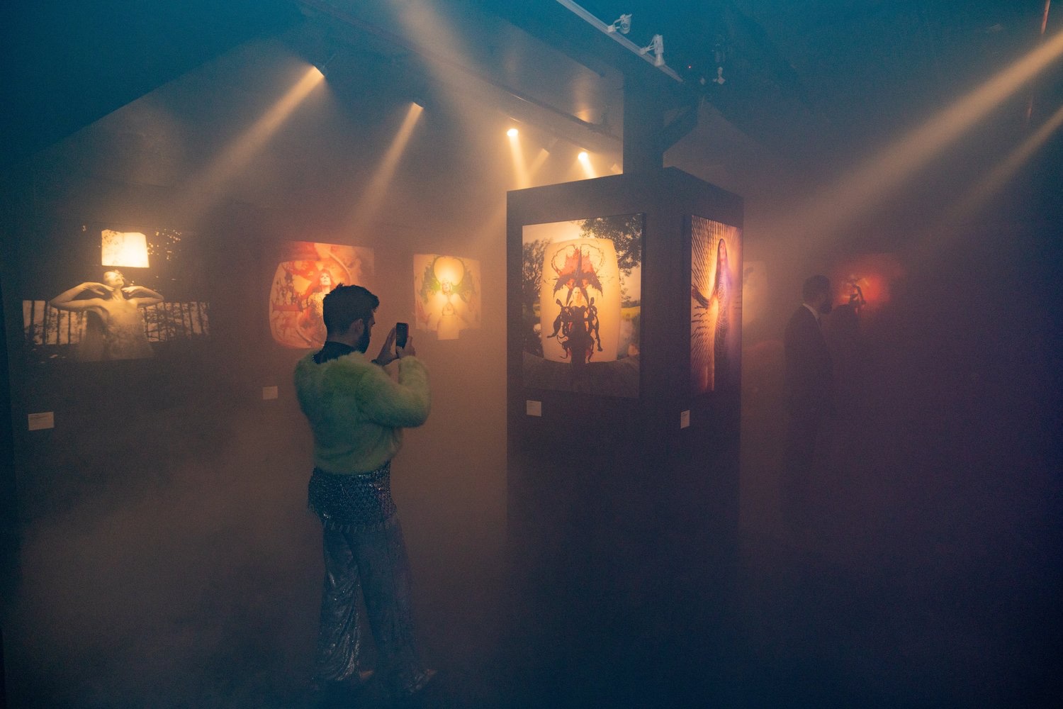 Visitor in a lime fur jacket photographs artwork in the misty Jordan Milligan gallery