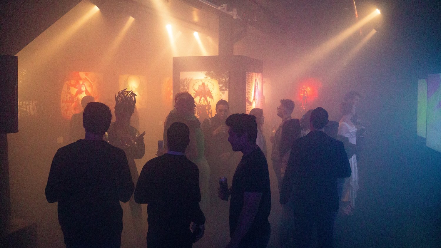 Silhouetted guests view illuminated portraits through colored fog at the Jordan Milligan show