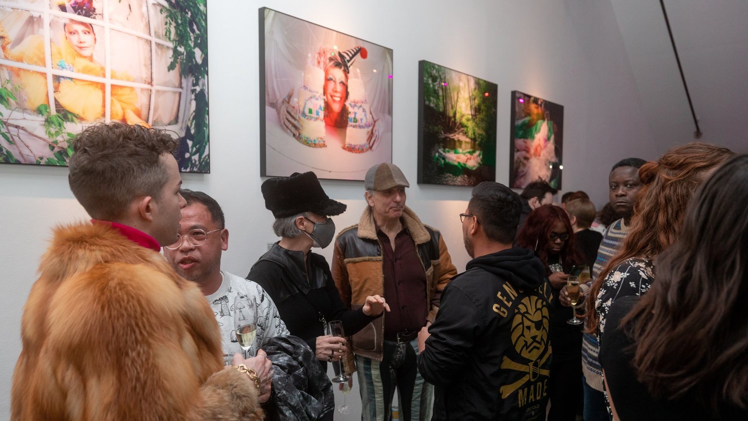 Crowd with champagne and fur hats mingles beneath portraits with whimsical birthday themes