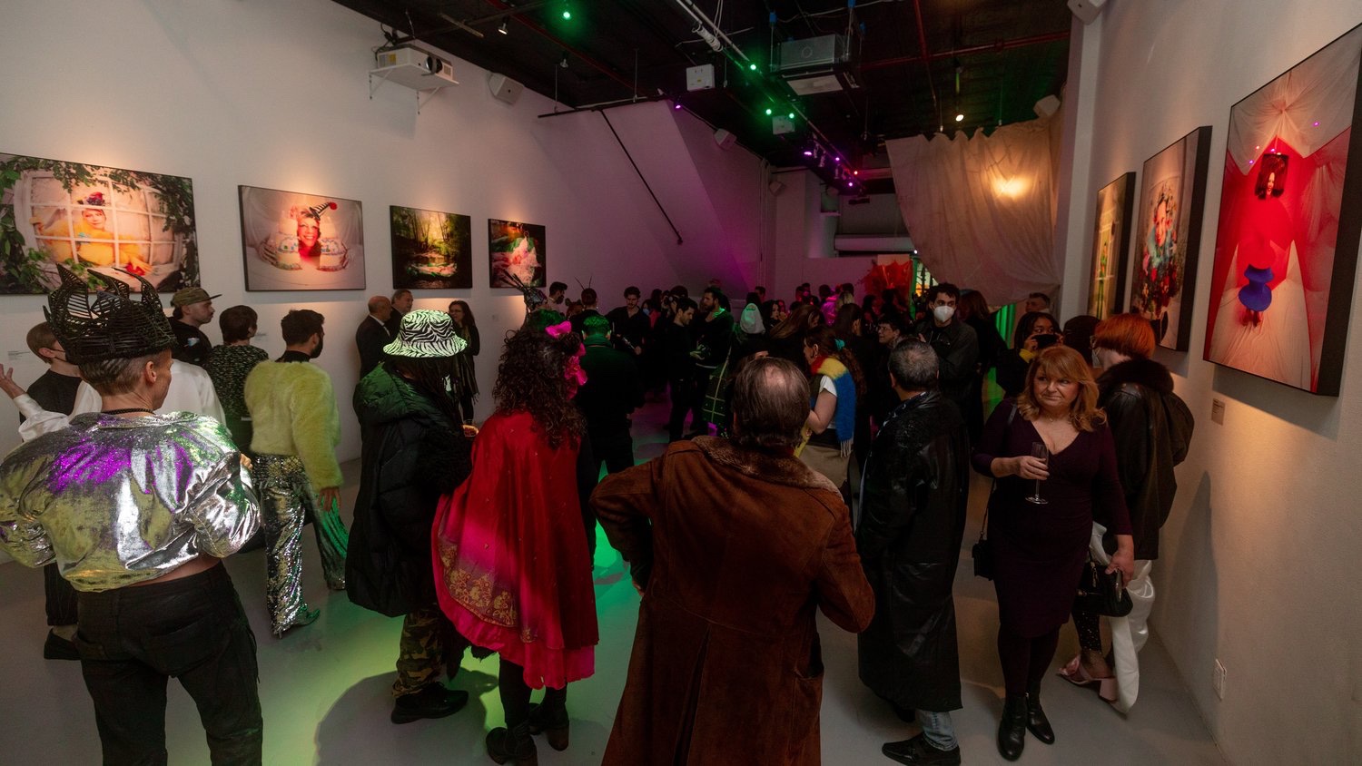 Costumed visitors fill the gallery as green light washes over the Jordan Milligan opening