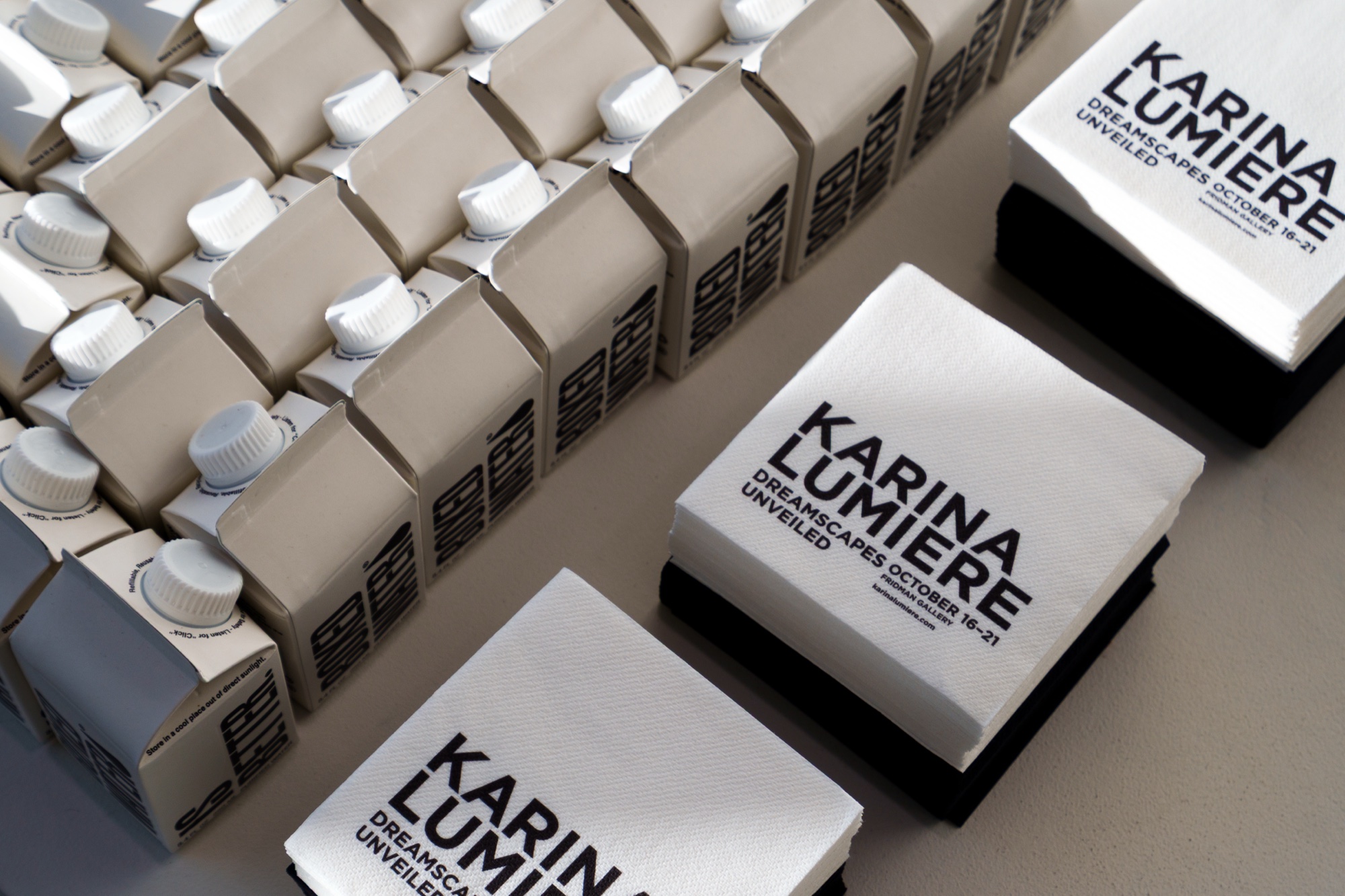 Stacks of Karina Lumiere Dreamscapes Unveiled printed cards beside rows of small white boxed bottles