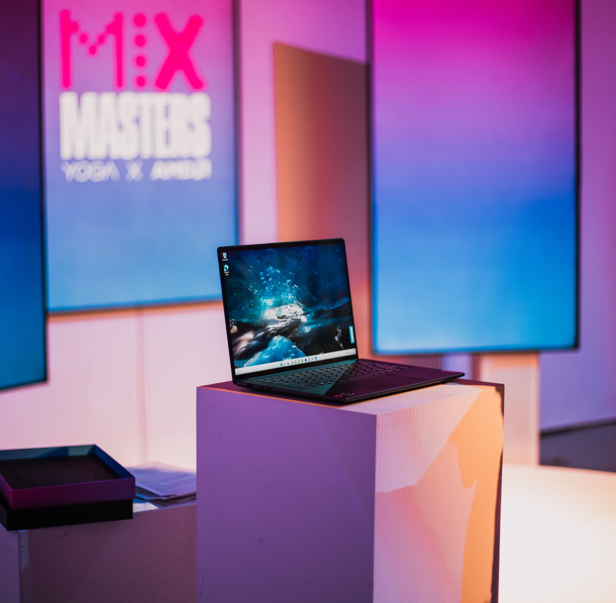 An open laptop stands on a white plinth in front of a pink Mix Masters sign and colourful backlit panels