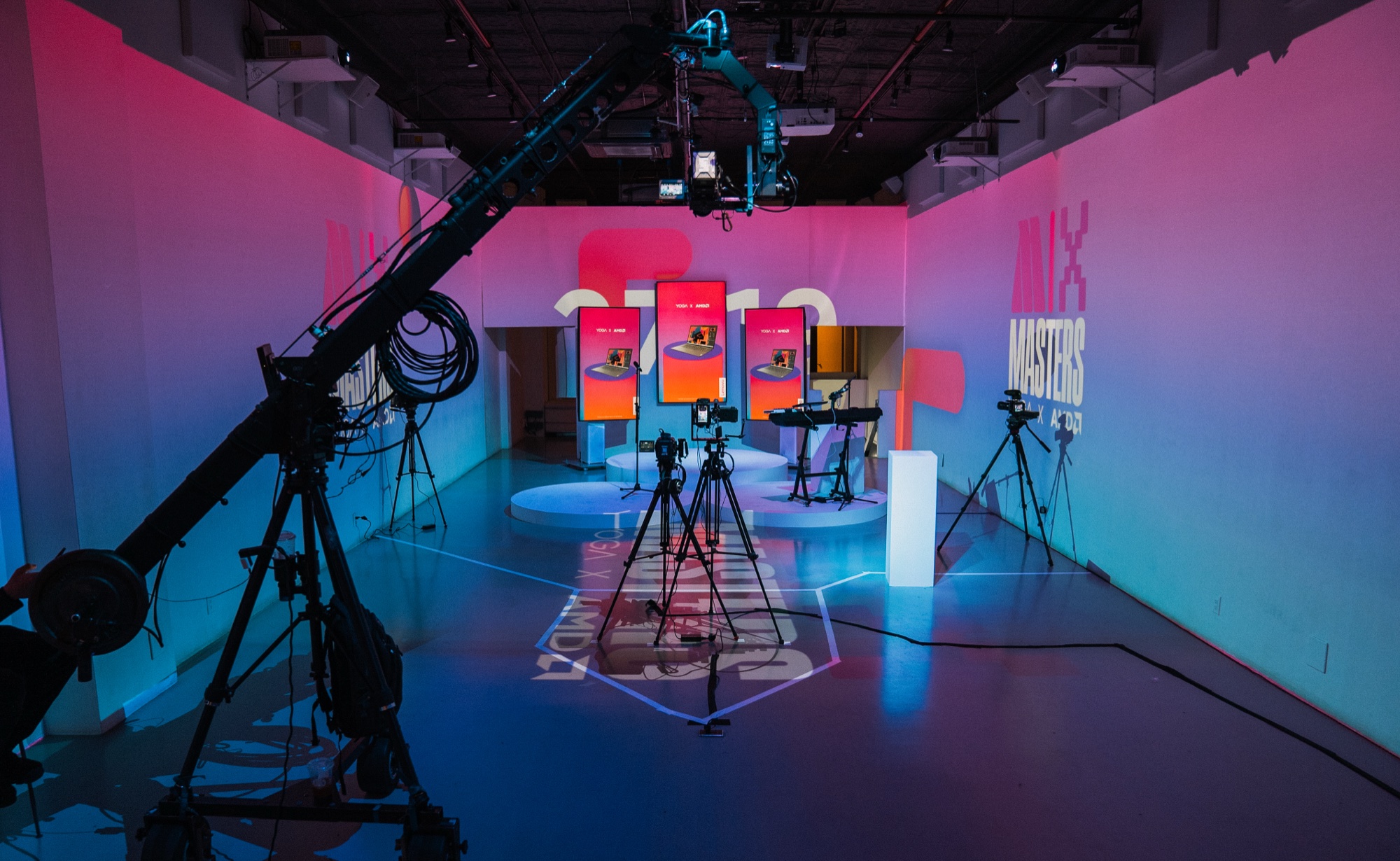 Camera jib and tripods set up in a pink and blue lit studio with screens on plinths and Masters signage